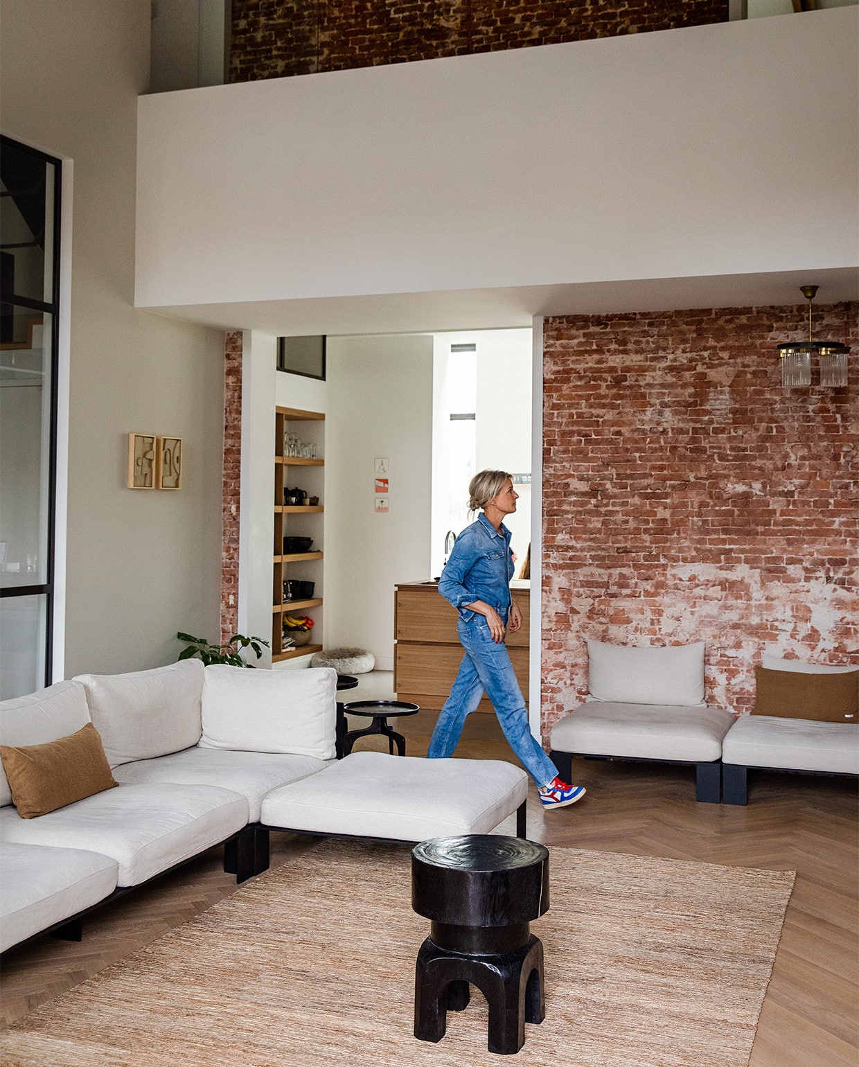 Bank, kussens en vloerkleed van Serax via Studio AnoukB. Bijzettafel voor de bank Café Cote. Vloer Haarlemse Houthandel. Bijzettafels achter de bank en servies op planken Just another shop. Lamp herkomst onbekend. Kunstwerken Edith Beurskens. vtwonen 08-2021 | styling Ilona Jongepier | fotografie Dana van Leeuwen