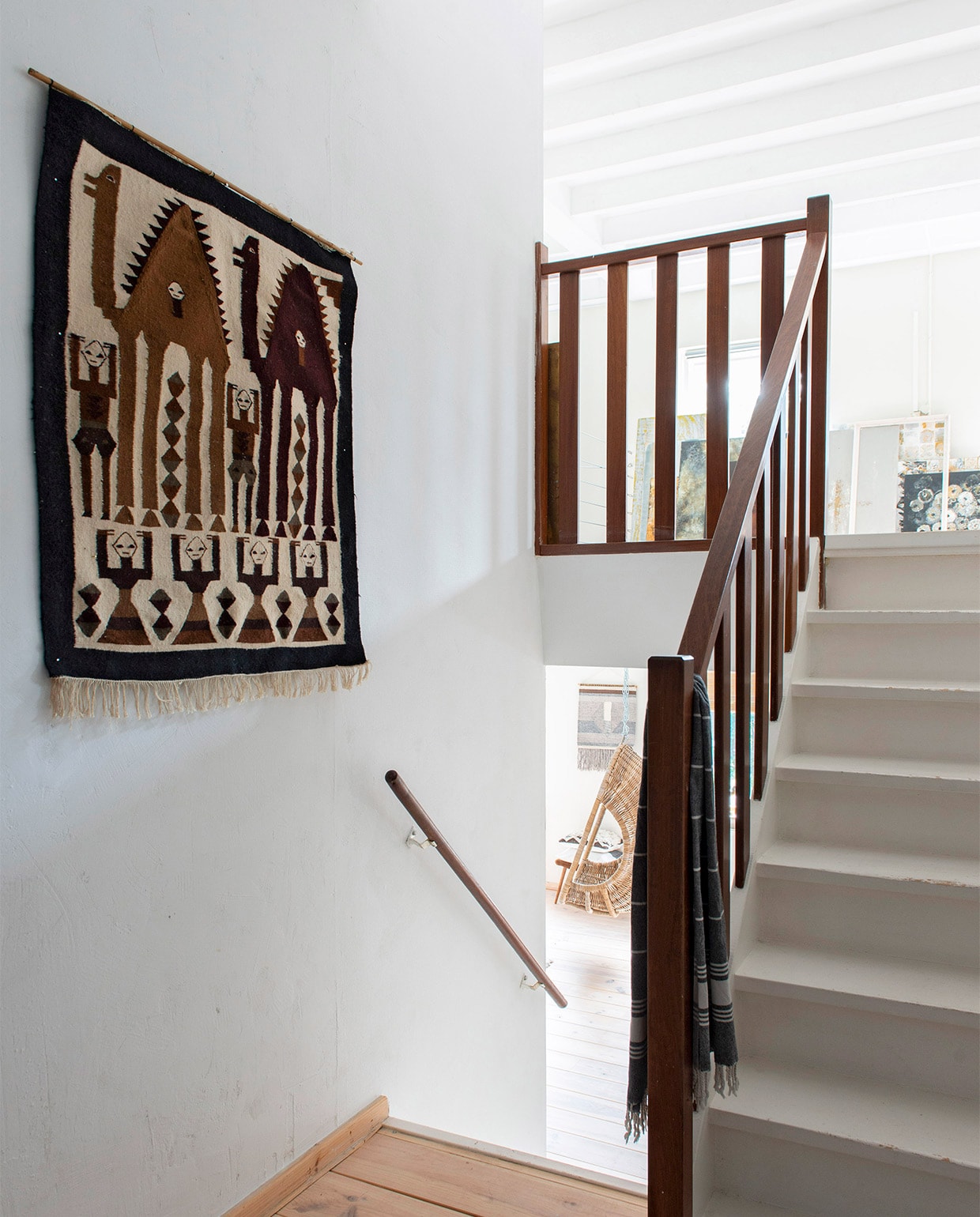Naast de trap die naar het atelier leidt, hangt een tweedehands wandkleed. vtwonen 08-2021 | productie de Binnenkijkers | styling Jeske Weel | fotografie Caroline Coehorst | tekst Christine van der Hoff