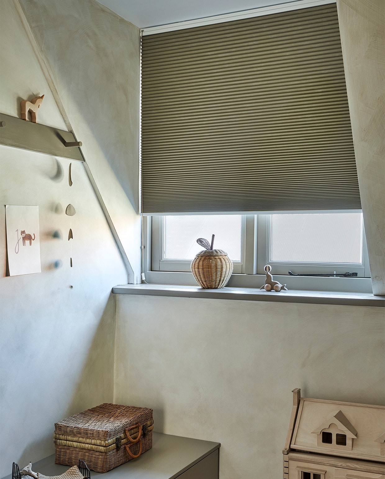 Verduisterend plisségordijn, op maat gemaakt, in kleur Donkerbeige (18070) . M.m.v. ilovespeelgoed.nl (poppenhuis, zeeleeuw van Konges Sløjd), bauwerkcolour.com (muurverf in kleur Witch Hazel), fermliving.com (rieten appelmand), oliella.com (gevlochten koffer), fishonthemoon.com (zwart mini-bed van Maileg), richardvanmeerveld.nl (op maat gemaakte lage opbergkast), littlegreene.nl (verf kast in kleur Silt). Overig privébezit. vtwonen 09-2021 | productie Tanja Saarberg | styling kim van Rossenberg | fotografie Peggy Janssen
