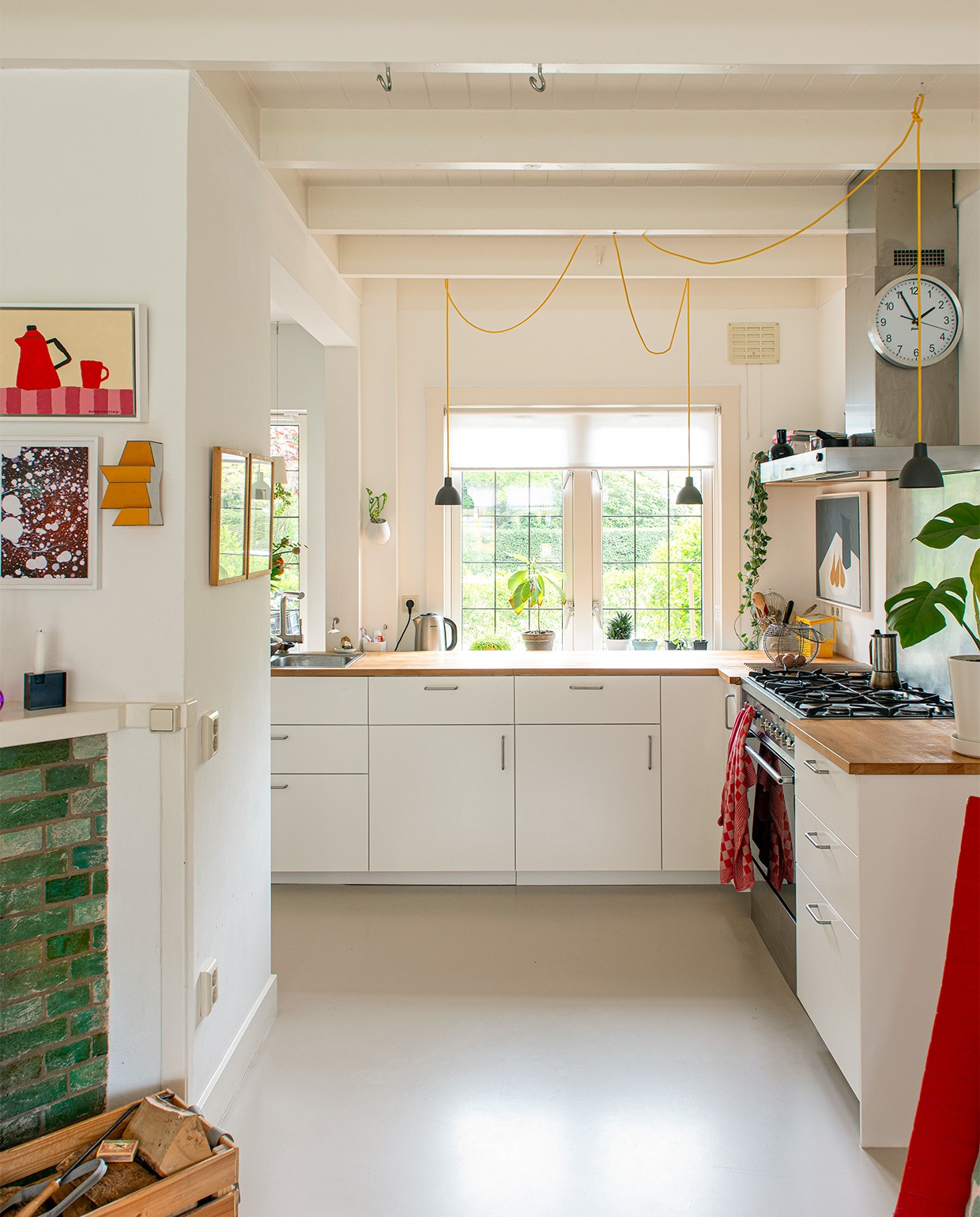 Keuken, plantenpot aan muur en bloempot op aanrecht Ikea, hanglampen Told Bold van Louis Poulsen, vloer Coaton in kleur RAL 2005-Y50R, kunstwerken boven aanrecht van Alessandra Taccia en Lon Pennock. vtwonen 07-2021 | styling Jeske Weel | fotografie Caroline Coehorst