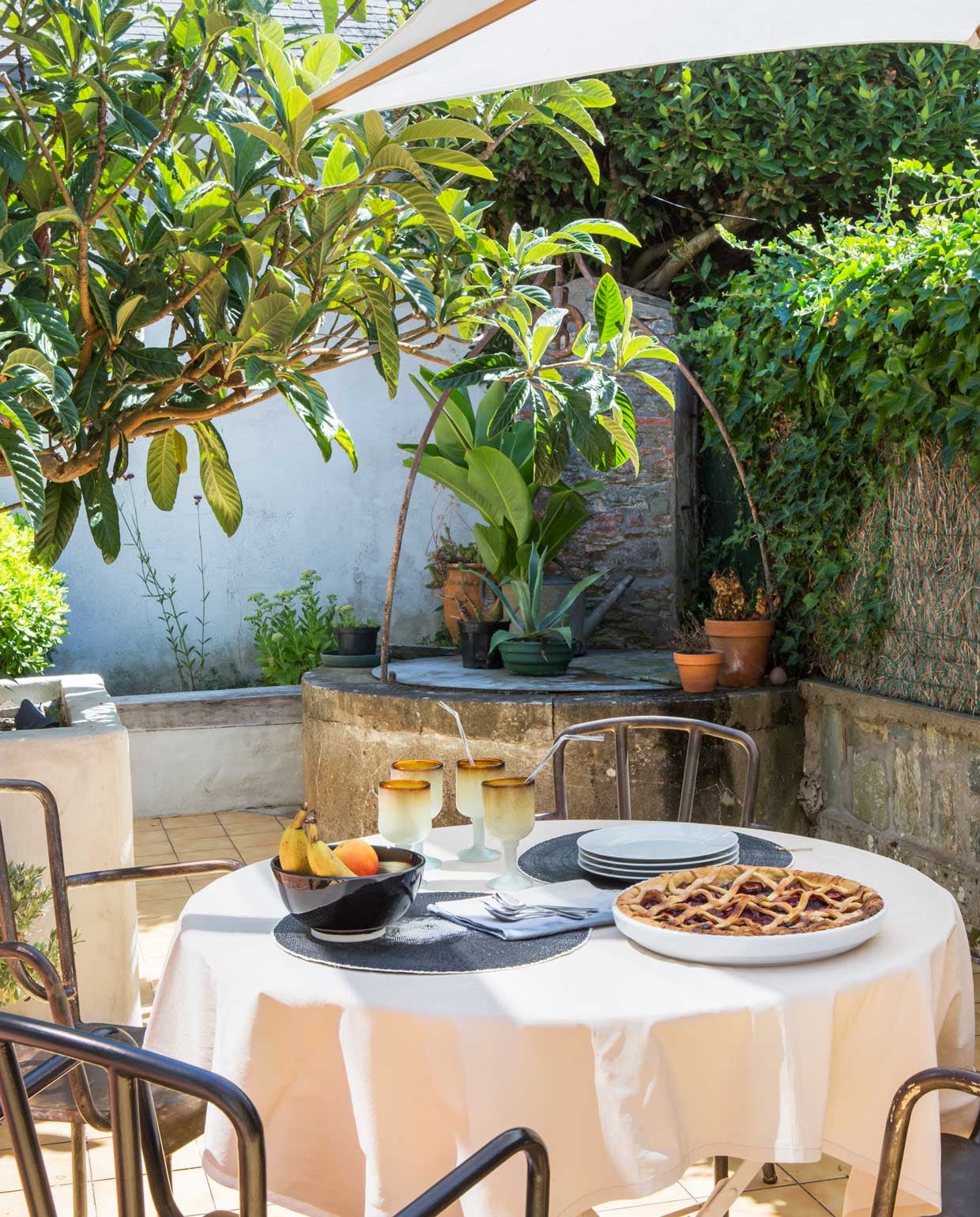 Het terras bij het huis is zonnig, maar door een schaduwdoek, witte muren en mediterrane planten toch koel. vtwonen special binnenkijken 06-2021 | productie Anne-Catherine Scoffoni | fotografie Pauline Legoff