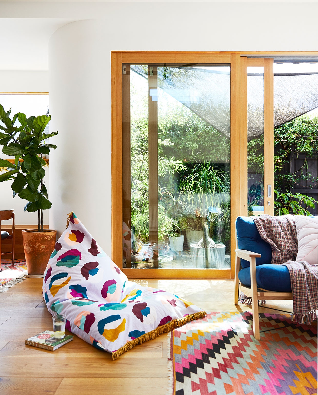 In de moderne aanbouw geven houten kozijnen warmte aan de witte muren. Zitzak Sage x Clare. Kleed uit Turkije. Bank GlobeWest. vtwonen binnenkijk special zomerhuizen 07-2021 | productie &amp; styling Living Inside | fotografie Armelle Habib