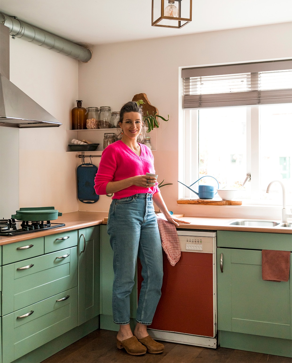 Verfkleur keuken Chappell Green van Farrow &amp; Ball. Vaatwasser Marktplaats. Pan Terracotto Sambonet. Metalen wandrek in U-vorm Ikea. Pannenrek Ikea. Grillplaat Le Creuset. Aardewerken ovenschaal fairtrade winkel. Keukendoeken Dille &amp; Kamille. Lamellen Luxaflex. Lamp Praxis. Overige kringloopwinkel. vtwonen 07-2021 | fotografie Muk van Lil
