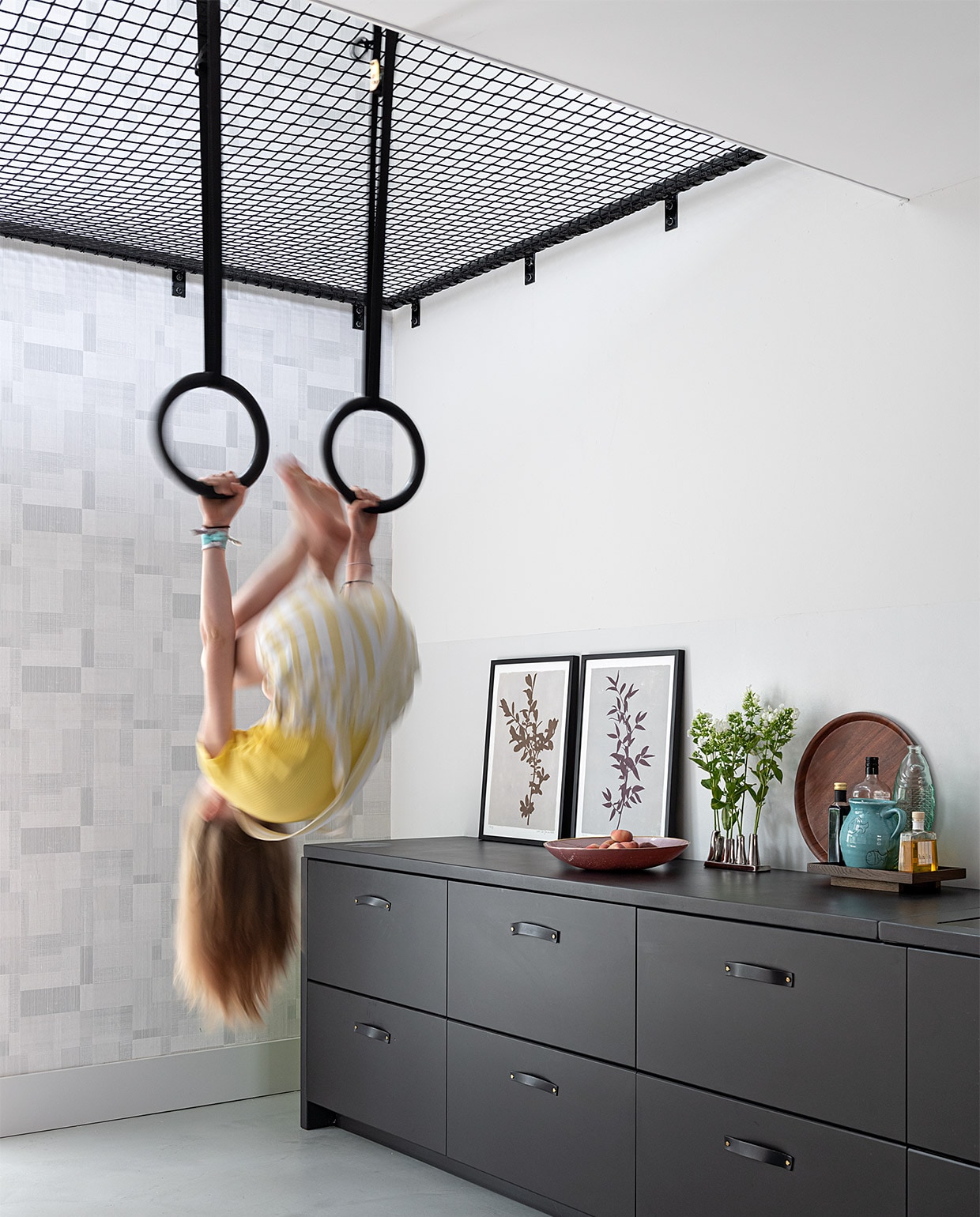 Speelnet gebouwd door bouwbedrijf Klomp. Net van Van Beelen NTN. Op de vloer Ultratop in betonlook, behang op muur rond raam Norrköping Engblad &amp; Co. Keukenkasten en fronten Kungsbacka Ikea. Vezelcementplaat door Evolve via Leurs Interieurbouw. Roze fruitschaal, leren ladegrepen Loods 5. Lijsten P. Zilveren vaasje kringloop. Rond houten dienblad H&amp;M Home. Vierkant dienblad, blauwe kan Ikea. Zwarte ringen . vtwonen 07-2021 | styling Sharon Roest | fotografie Caroline Martinot | tekst Renske Schriemer
