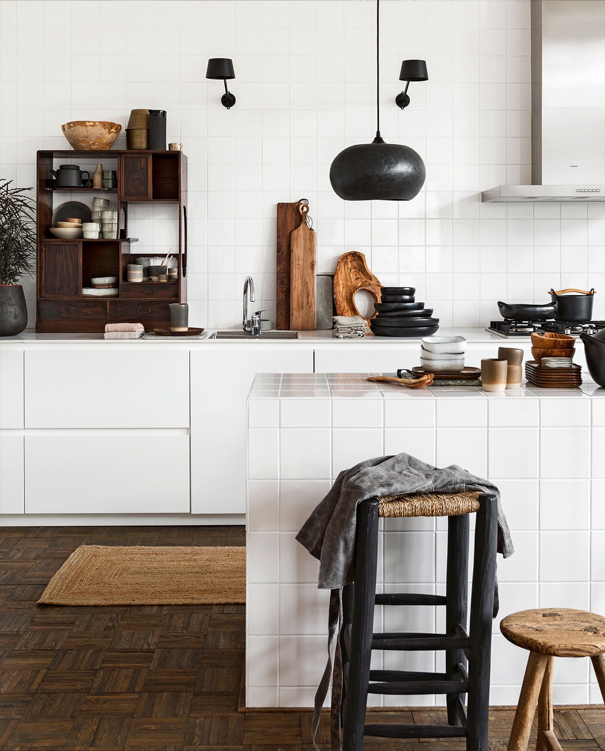 Zwarte wandlampen per stuk € 265,- (tonone.com). Wengéhouten vaas van Scapa Home € 145,- (vtwonen.nl). Antiek Japans theekastje van eind 1800, 75x30x96 cm (bxdxh) € 775,- (interieur-vivre.nl). Op en in het kastje: grote olijfhouten schaal € 87,50 (twinningshop.nl), messing vaas € 64,95, licht beige mokjes per stuk € 9,50, rechthoekig wit schaaltje € 34,95, camelkleurige schaaltjes per stuk € 13,95, wit schaaltje € 15,95 (loftloft.nl), matzwarte karaf € 28,-, matzwarte theepot € 34,- (kinta.nl), bottle vaas Walnut € 29,-, schaaltjes Walnut per stuk vanaf € 27,-, mokje Walnut € 26,-, mokjes Basalt Grey per stuk vanaf € 25,-, latte mok Basalt Grey € 28,-, eierdopjes Basalt Grey per stuk € 15,-, lepels Basalt Grey groot per stuk € 17,-, middel per stuk € 15,-, klein per stuk € 12,50 (annemiekebootsceramics.nl), marmeren schaaltjes per stuk € 11,25 (stuffdesign.dk). Op het aanrecht: theedoekjes Essential Nude van Södahl per 2 € 24,95, beige theedoeken van vtwonen per stuk € 10,46, zwarte gietijzeren braadpan Sarpavena van Iittala € 192,15, Nordic Kitchen steelpan van Eva Solo € 77,95 (vtwonen.nl), betonnen plank € 16,50, sheeshamhouten bordje € 28,75, donkere hoge sheeshamhouten plank met leren band € 39,95, acaciahouten plank met gaatje € 31,95, grijze betonnen plank € 16,50 (stuffdesign.dk), kannetje Basalt Grey € 59,- (annemiekebootsceramics.nl), grote olijfhouten schaal met gat € 87,50, olijfhouten slacouvert € 16,- (twinningshop.nl), zwarte keramieken schalen, van onder naar boven grote platte per stuk € 63,50, kleine platte per stuk € 38,95, kleinste per stuk € 15,95, zwarte ovenschaal € 44,- (loftloft.nl). Op het keukeneiland: groene marmeren plank met leren band € 25,- (stuffdesign.dk), platte camelkleurige schaaltjes per stuk € 17,95, witte schaaltjes per stuk € 15,95, latte mok Basalt Grey € 28,-, mokjes Basalt Grey per stuk € 25,- (annemiekebootsceramics.nl), stapel platte camelkleurige schaaltjes per stuk € 17,95, witte kleine platte schaaltjes per stuk € 13,75, zwarte keramieken schaal met deksel € 64,95 (loftloft.nl), olijfhouten schaaltjes per stuk € 22,25 (twinningshop.nl). Zeegras vloerkleed van Bloomingville € 99,- (vtwonen.nl). Hanglamp Pebble medium € 244,90 (ayilluminate.com). Hoge kruk met sisal zitting € 115,-, uniek oud houten krukje € 125,-, wandlampen per stuk € 265,-, eikenhouten mozaïek vloer per m² circa € 40,- (loftloft.nl). Vintage grijs leren schort € 115,- (stuffdesign.dk). vtwonen 01-2019 | styling Moniek Visser | fotografie Stan Koolen