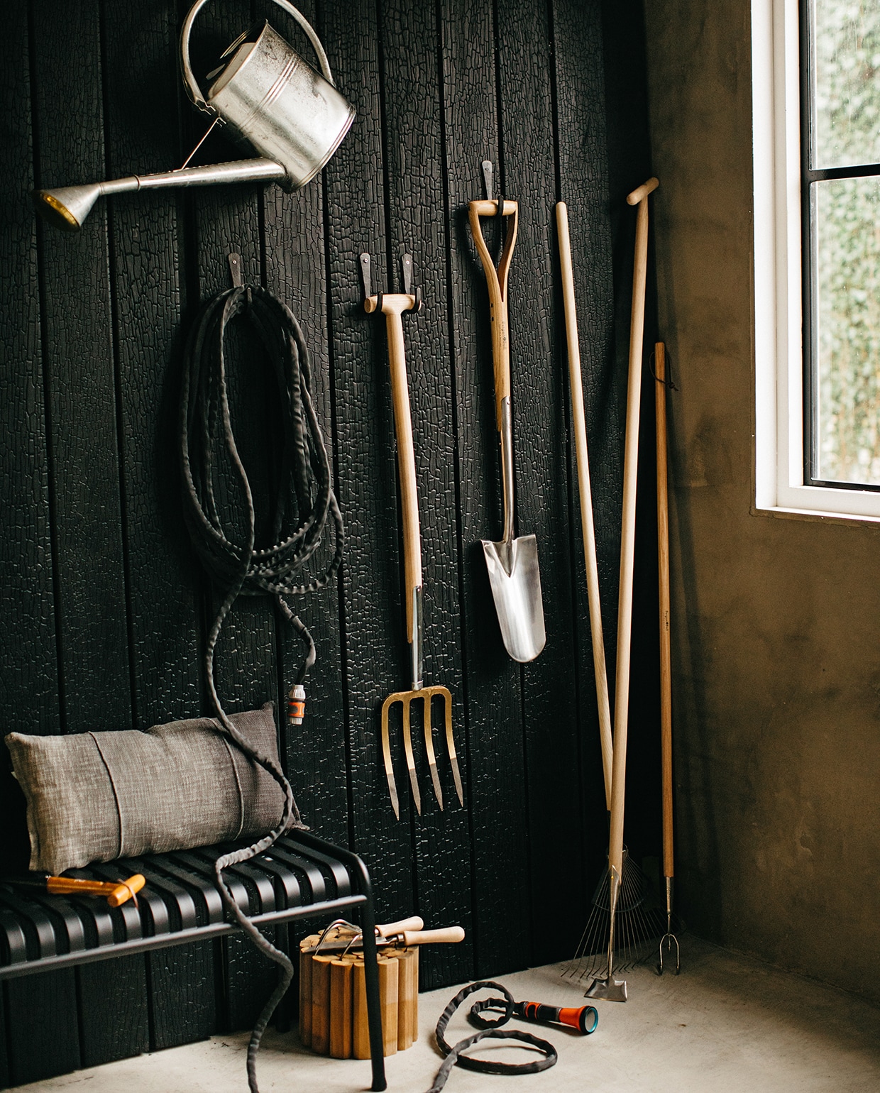 Wand bekleed met Marugame planken van gebrand Accoya hout (zwarthout.com). Haken voor gereedschap (loods5.nl). Gieter verzinkt, 8 liter (wiltfang.nl). Tuinslang Liano van Gardena (fonq.nl). 4-tands spitvork (gamma.nl). Verplantspade, schoffel, grashark, cultivator, handcultivator, onkruidschepje (wiltfang.nl). Houten rolborder (hornbach.nl). Tuinbank Palissade van Hay (fonq.nl). Plantstok (praxis.nl). Kussen (loods5.nl). vtwonen tuin special 1 2020 | styling Moniek Visser | fotografe Danique van Kesteren