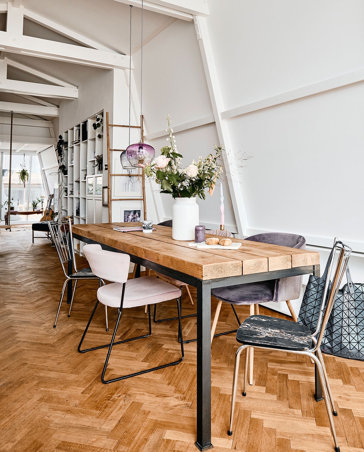 Eettafel en metalen stoelen Van Dijk &amp; Ko. Lichtroze stoel Giga Meubel. Paarse stoelen en paarse kaars onbekend. Witte vaas Bloomon. Kaars Diptique. Marmeren plank House Doctor. Kandelaar Sissy-Boy. Draaikaars Decor. Ladder en donkerblauwe en paarse hanglampen Loods 5. Posters Desino. Inbouwkasten Ikea. Tas Issey Miyake. vtwonen 06-2021 | productie CocoFeatures | fotografie Roos Oosterbroek