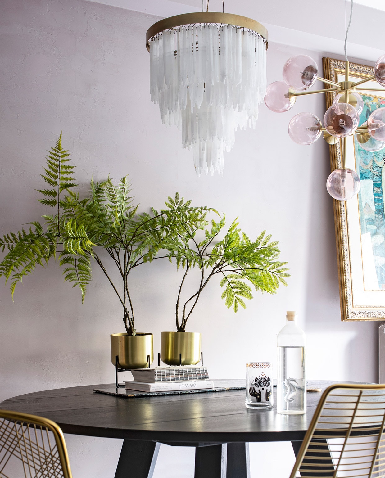 Ronde tafel van Leeelijk, de messing stoelen zijn van Zenza. Plantenhouders met messing potten Salix van Made, erin zijdeplanten van Silk-ka. Hanglamp met bollen van Made, lamp met hangende glazen pegels van Zenza. Vloerkleed van Rozenkelim, opgezette pauw van Taxidermy Amsterdam. Fles op tafel van Regalo Gallery, glas en roze kop-en-schotel van Anthropologie, blauwe waxinelichthouder van Zara Home. Het schilderij op de radiator is een souvenir uit Bali. vtwonen 06-2021 | productie Insidehomepage | styling en tekst Inge van Lieshout | fotografie Louis Lemaire | tekstbewerking Renske Schriemer