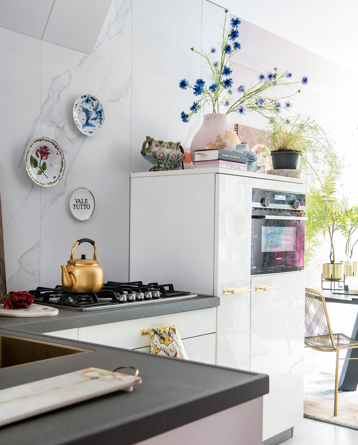 Goudkleurige ketel op het fornuis uit Marrakesh. Op de kast roze PS-vaas van Ikea, erin bloemen van Silk-ka, blauwe vaas van Anthropologie. vtwonen 06-2021 | productie Insidehomepage | styling en tekst Inge van Lieshout | fotografie Louis Lemaire | tekstbewerking Renske Schriemer
