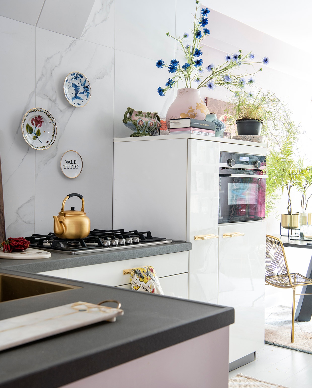 Goudkleurige ketel op het fornuis uit Marrakesh. Op de kast roze PS-vaas van Ikea, erin bloemen van Silk-ka, blauwe vaas van Anthropologie. vtwonen 06-2021 | productie Insidehomepage | styling en tekst Inge van Lieshout | fotografie Louis Lemaire | tekstbewerking Renske Schriemer
