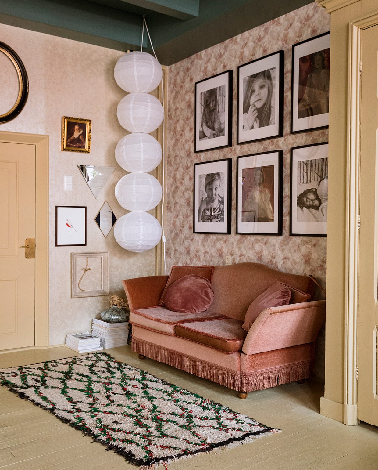Behang links Fenton in goud en rechts Quartz van 1838 Wallcoverings. Verfkleur plafond Peacock en overig houtwerk Bisquit van Painting The Past. Tweedehands bank gekocht via Instagram. Vloerkleed The Souks. Geometrische spiegels Living Once en &amp;Klevering. Lijsten her en der verzameld. Pot op stapel tijdschriften Loods 5. Bollampen van rijstpapier Ikea, zelf aan elkaar geregen. Ingelijste fotoportretten van de kinderen en schilderijen van Grace Spiegel. vtwonen 06-2021 | styling Ilona Jongepier | fotografie Dana van Leeuwen