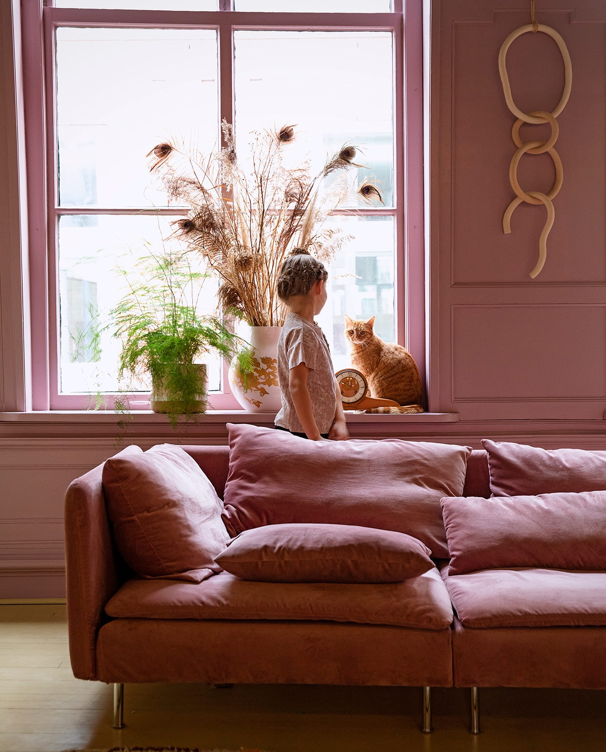 Verfkleur Velvet Plum van Painting The Past. Bank Söderhamn van Ikea met velvet hoes van Bemz. Plant Bloembinderij Rosafleur in pot Nørd conceptstore. Vaas Hella Jongerius voor Ikea, pluimen herkomst onbekend. Schouwklok van Susannes ouders. Keramische wandhanger Lydia Elisabeth Pottery. vtwonen 06-2021 | styling Ilona Jongepier | fotografie Dana van Leeuwen