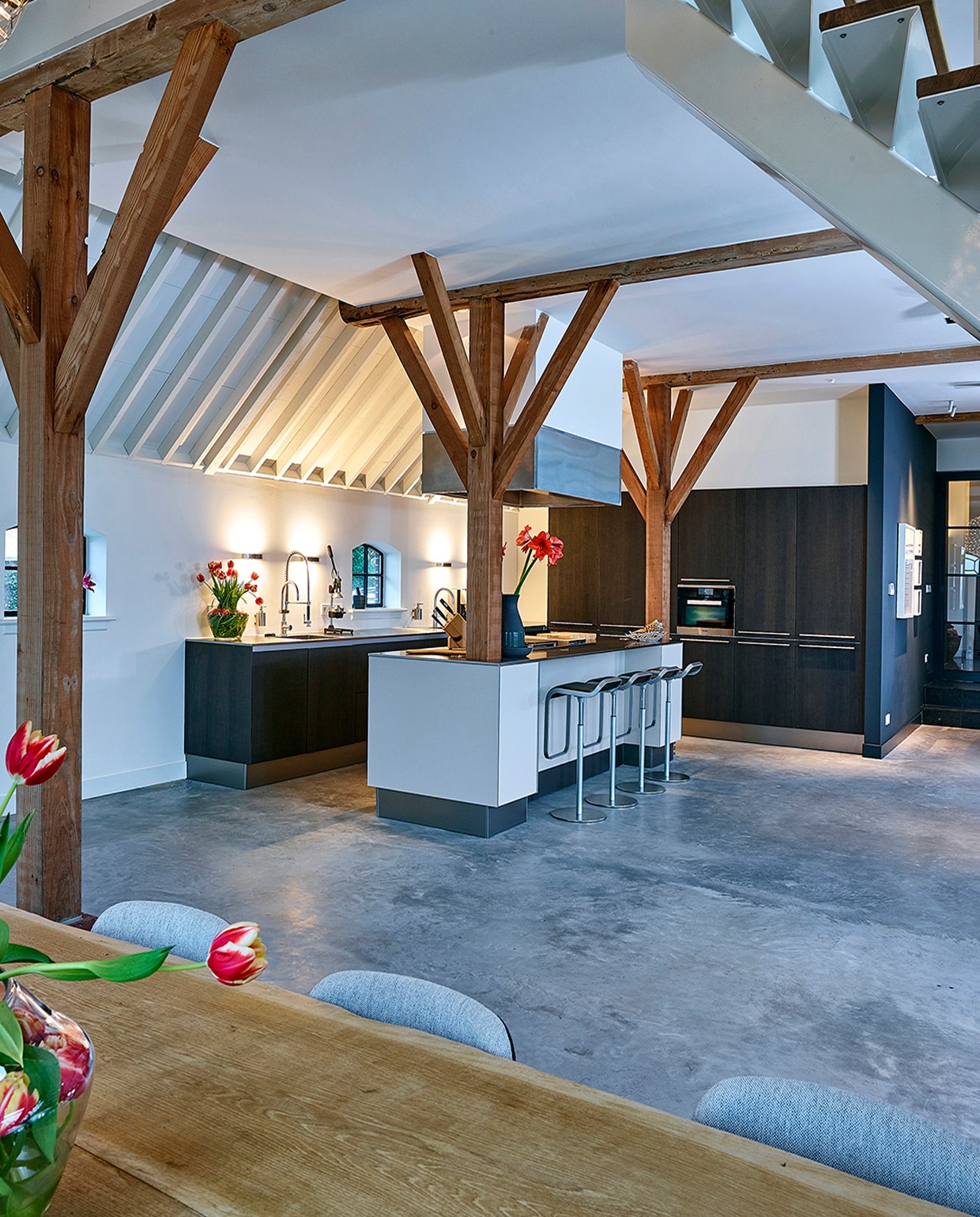 Modern landelijke keuken in Ouderkerk aan de Amstel met fronten van antraciet eiken, een rvs werkblad en een met rvs ommantelde schouw boven het kookeiland.