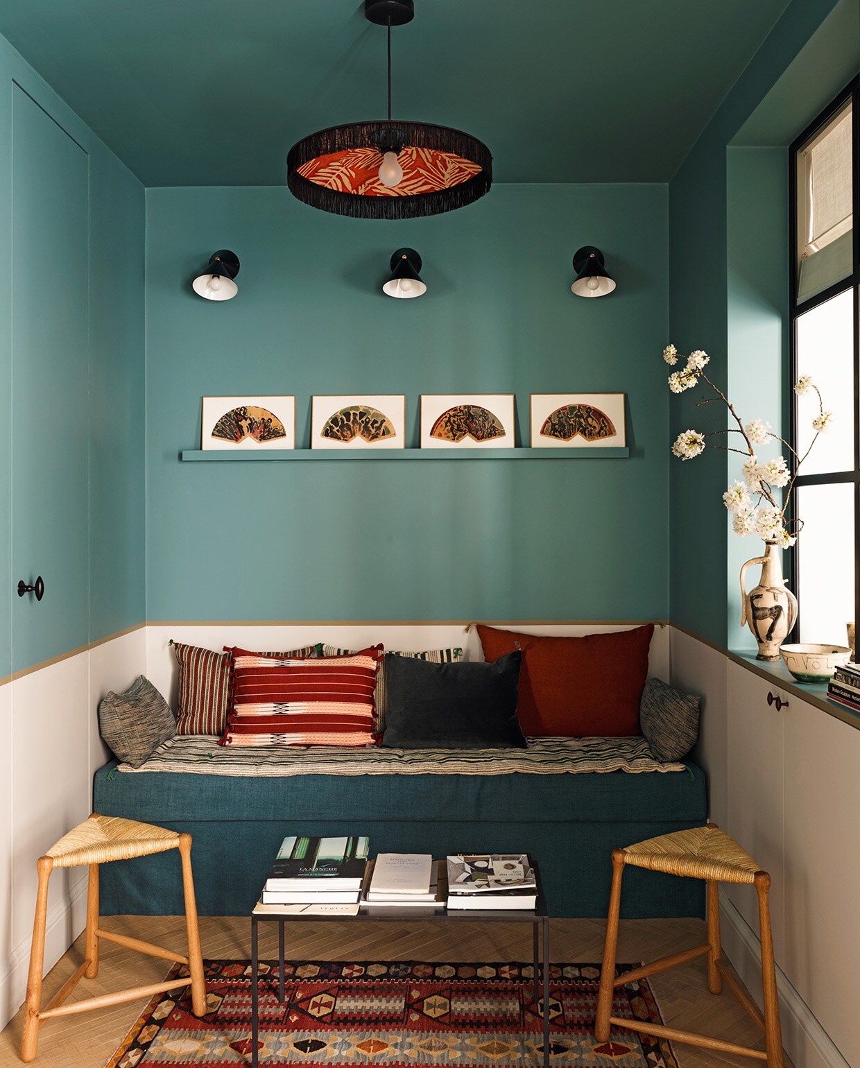 Blauwgroene verfkleur Mid Medici Blue, beige verfkleur Maya en kaki verfkleur Dark Stone, alles Ressource. Hanglamp Paloma Le Monde Sauvage. Wandlampen Atelier Areti. Kunstwerken op wandplank Claire Kito voor Galerie Peinture Fraîche. Kussens en salontafel Caravane. Vloerkleed Kilims Ada. Driepootkrukken Ailleurs Paris. vtwonen special tiny houses 03-2021 | styling Marianne Evennou | fotografie Stephan Julliard