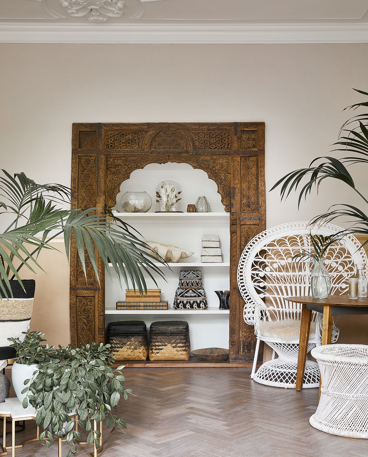 Oude poort meegenomen uit India. Pauwstoel, manden, plantentafels en zelf wit gespoten kruk Zenza. Overige in kast souvenirs, vintage vondsten en dierbare items, zoals een naaidoos die Karins opa heeft gemaakt. Tafel Raw Materials. vtwonen 06-2021 | productie Coco Features | styling Linda van der Ham | fotografie Peggy Janssen | Tekst Marlies Huisman, Mariska Keus