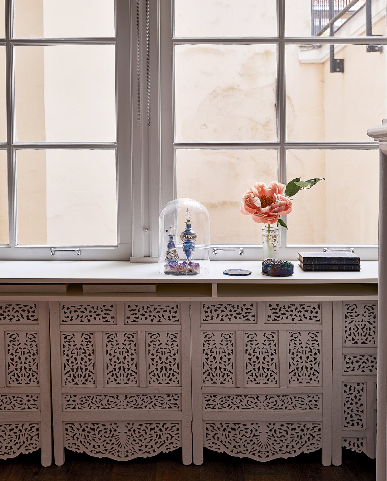 Radiatorombouw zelfgemaakt met een Indiaas kamerscherm. Stolp vintage vondst, erin twee parfumflesjes en een stuk amethist. Glas als vaas Zenza, oude kist uit Egypte. vtwonen 06-2021 | productie Coco Features | styling Linda van der Ham | fotografie Peggy Janssen | Tekst Marlies Huisman, Mariska Keus