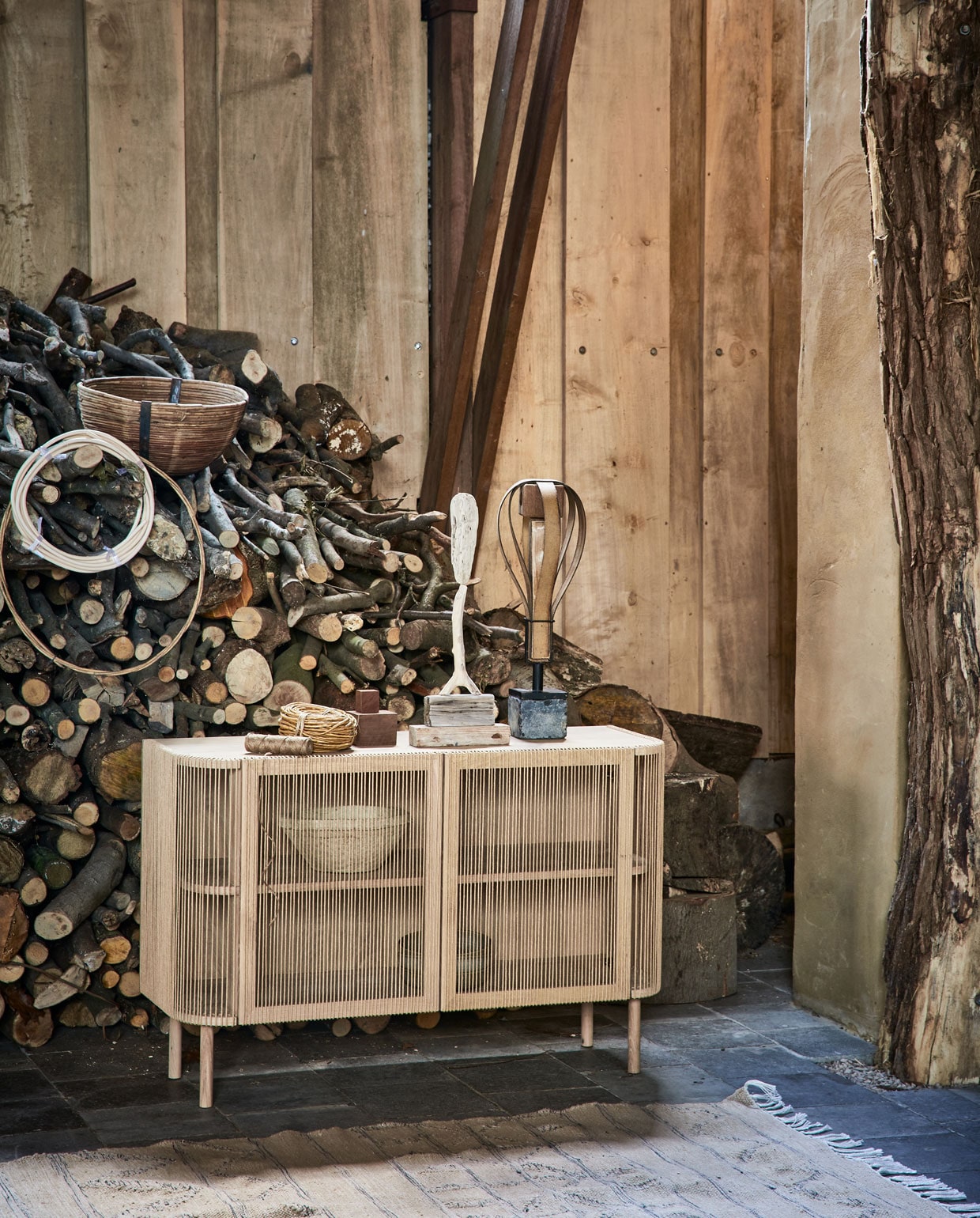 Dressoir Cord van wit geolied eiken , en touw, 120x80x40 cm (bolia.com). Kunstobjecten prijs op aanvraag (martvisser.nl). Grote rol goudkleurig koord, rotan ring prijs op aanvraag, bij elkaar gebonden spline (aangeenbrug.nl). Rotan mand, papier-maché schalen in dressoir (weldaad.com). Vloerkleed, 240×150 cm(hkliving.nl). vtwonen 05-2021 | styling Cleo Scheulderman | fotografie Jeroen van der Spek