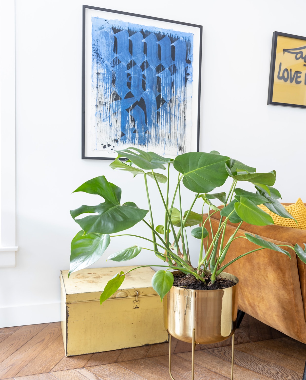 Kunstwerk Unruly van Niels ‘Shoe’ Meulman, gekregen van een goede vriend. Goudkleurig kunstwerk van de bevriende urban artist Laser 3.14. Bank Decor Amsterdam. Kussens Made. Vintage kist en poef cadeau gekregen. Plantenpot Zara Home. Eikenhouten vloer via de aannemer. vtwonen special tiny houses 2021 | fotografie Henny van Belkom
