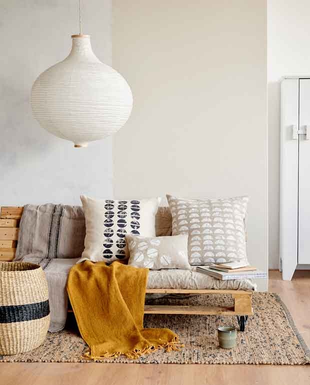 Linnen plaid van HKliving, grijze mok van House Doctor (wonenmetlef.nl). Vloerkleed, mand, gele plaid, hanglamp (ikea.nl). Kast Woood Gijs (basiclabel.nl).