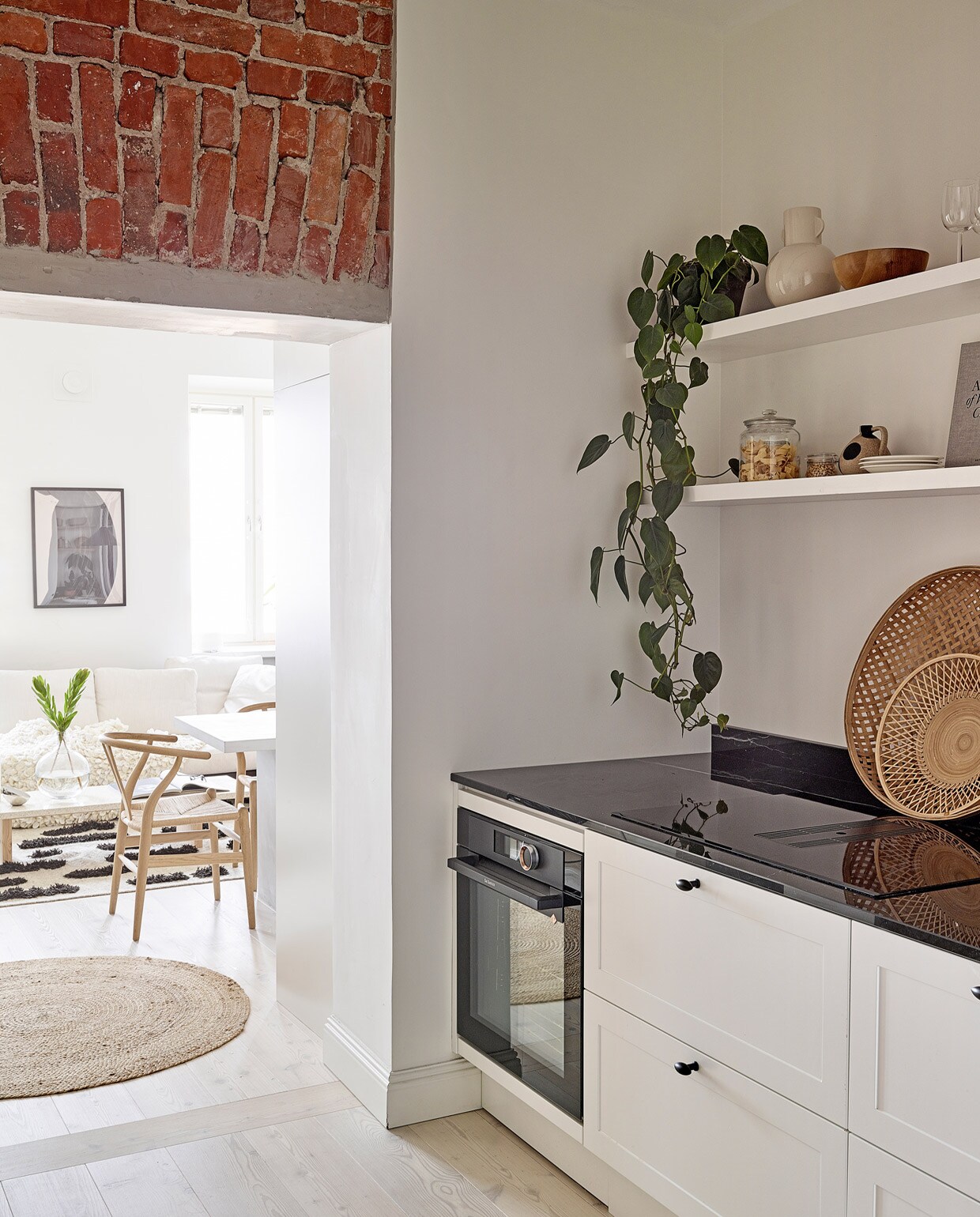 Rond vloerkleed Tine K Home. Eetkamerstoelen Wishbone Carl Hansen &amp; Son. Keuken Nixi. Beige vaas, glazen pot, witte borden en rotan dienbladen vintage. Houten kom herkomst onbekend. vtwonen special tiny houses | Productie Living Inside | Fotografie Krista Keltanen | Tekst Jonna Kivilahti | Tekstbewerking Adeline Mans