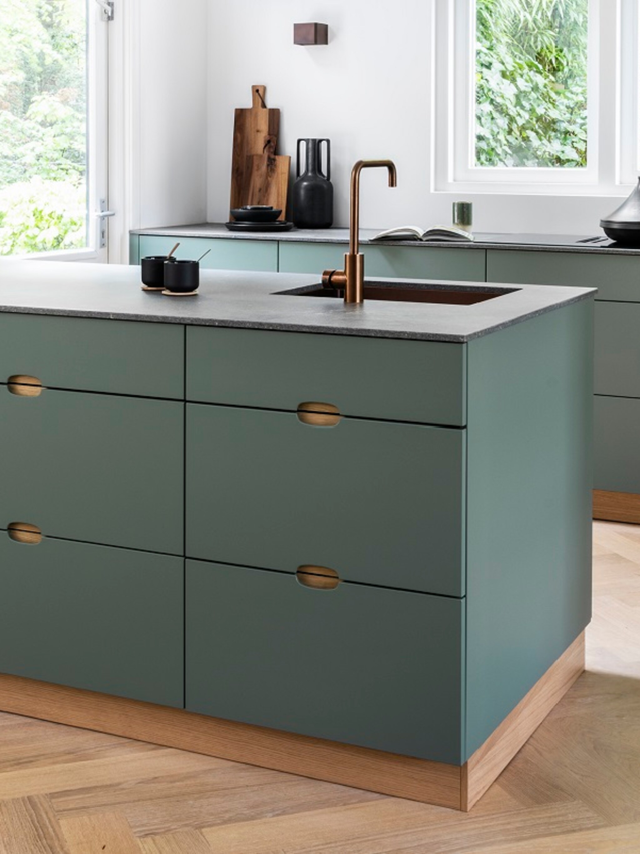 binnenkijken in een strakke groene keuken met koperen touch