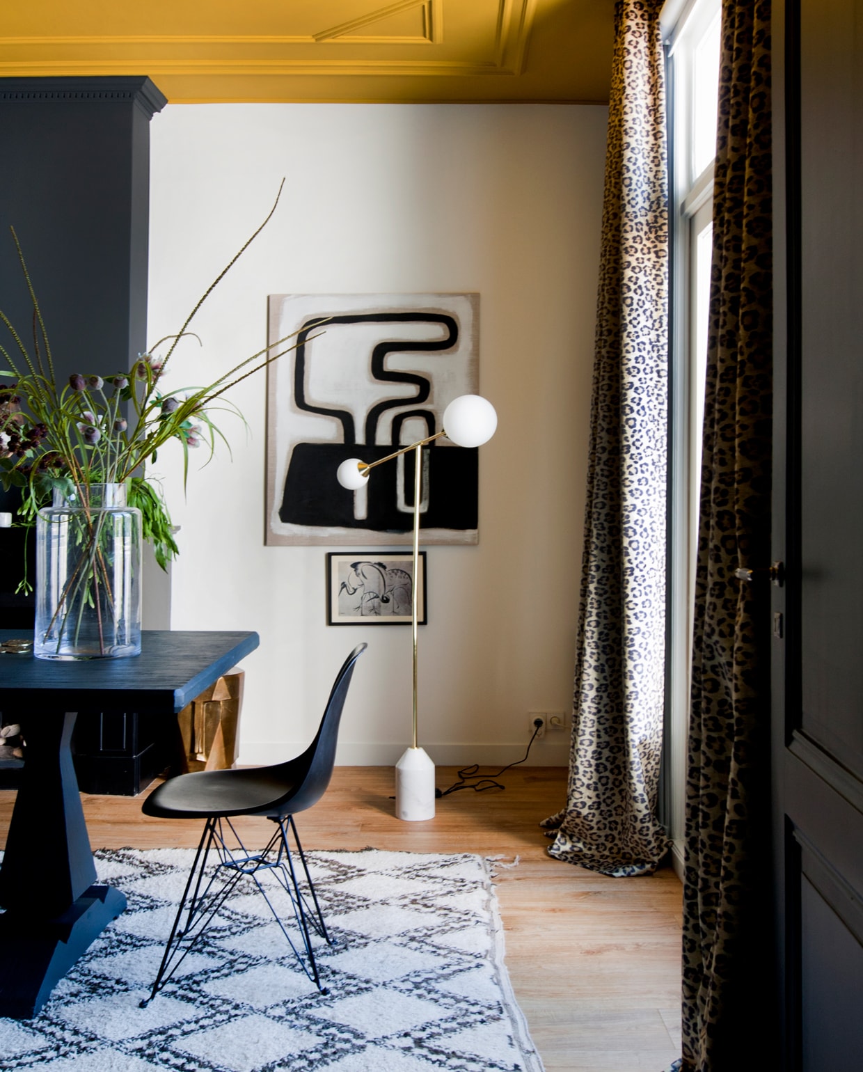 Eetkamer met spectaculair plafond in Lush Mustard van Flexa. Tafelverf: Off-Black van Farrow &amp; Ball. Het kunstwerk op linnen is gemaakt door mijn moeder.’ Lamp made.com, kunstwerkje HK Living, stoel DSR van Eames (Vitra), vintage berber uit Marokko. Vaas is een cadeau. Stoop Interieur leverde de velours stof met luipaardprint voor de gordijnen. vtwonen binnenkijken special 2019 | Styling en fotografie Theo-Bert Pot