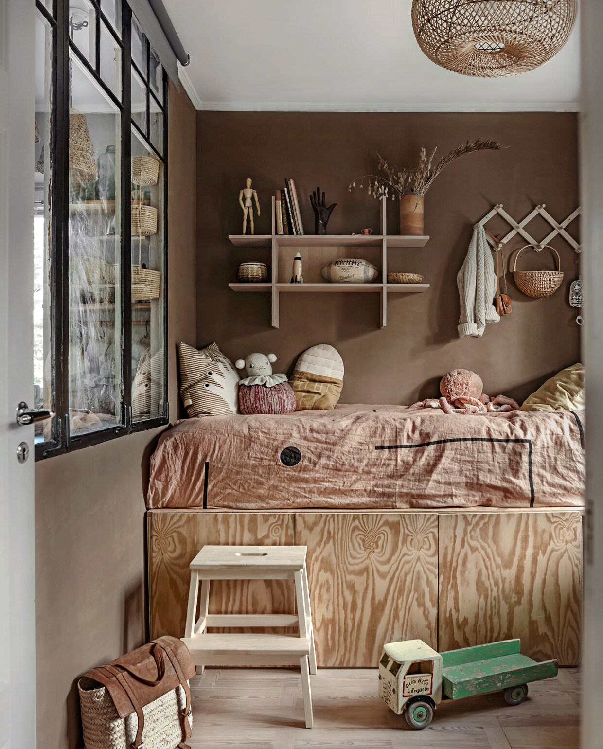 Bed met bergvakken zelfgemaakt, sprei uit Los Angeles, vergelijkbare muurkleur Colosseum van Carte Colori, wandrek en kruk Ikea, kussens Lucky Boy Sunday en Camomile London, mand vintage, vest Poudre Organic, speelgoed vintage. vtwonen 05-2021 | productie Taverne agency | styling &amp; tekst Mari Strenghielm | fotografie Anna Malmberg | tekstbewerking Christine van der Hoff
