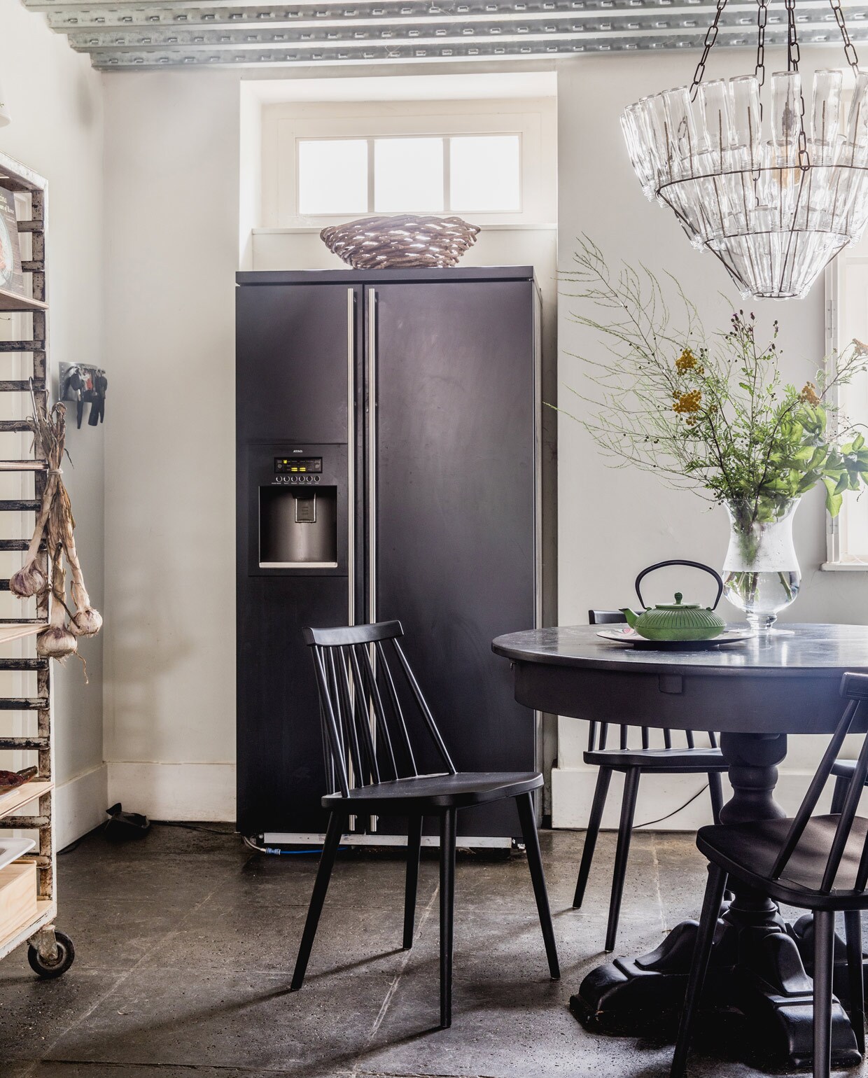 Keukentafel gekregen, zelf zwart geschilderd. Designstoelen J77 van Hay via Flinders. Vintage Chinese theepot uit Frankrijk, vergelijkbare te koop bij Dille &amp; Kamille. Vintage vlaaienrek Hof Tongerlo. Lamp van lege flessen Leitmotiv. Koelkast herkomst onbekend. vtwonen 05-2021 | productie Features &amp; More | styling Wilma Custers | Fotografie Ivar Janssen
