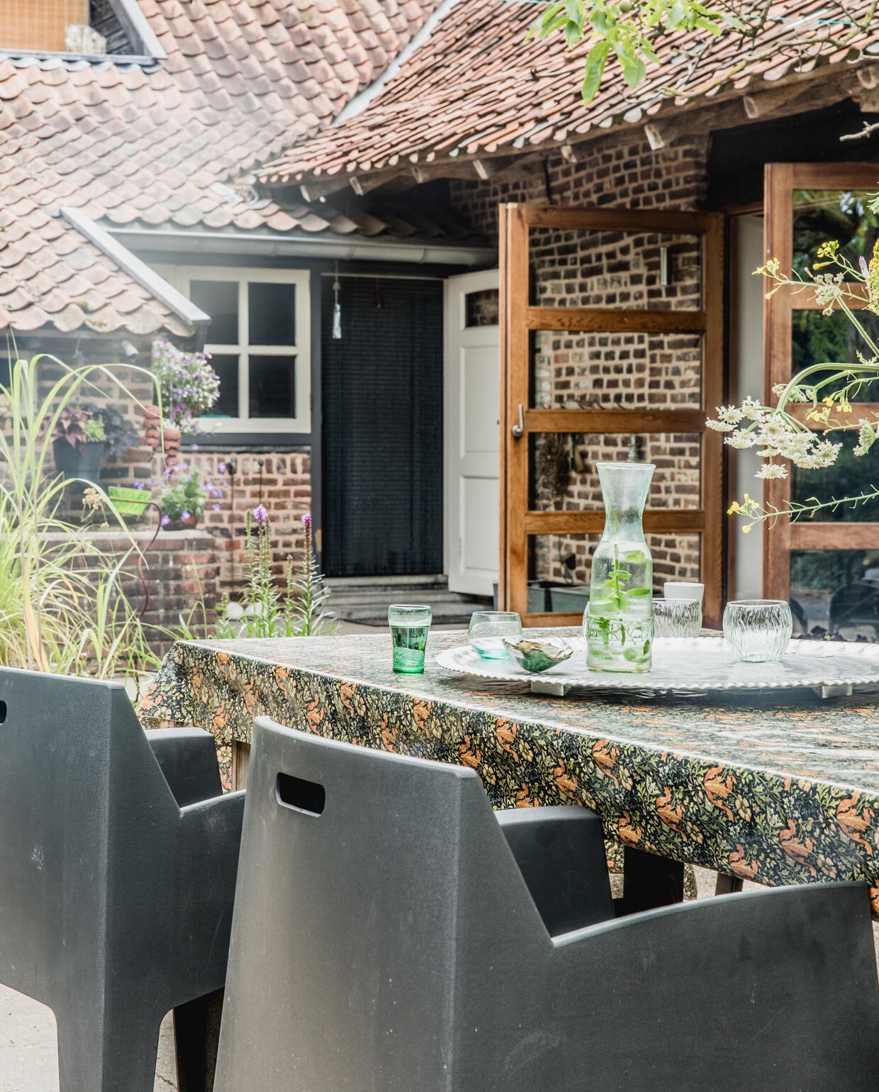 Houten buitentafel gemaakt door Jan. Weerbestendig tafelkleed William Morris. Tuinstoelen Leen Bakker. Overig herkomst onbekend. vtwonen 05-2021 | productie Features &amp; More | styling Wilma Custers | Fotografie Ivar Janssen