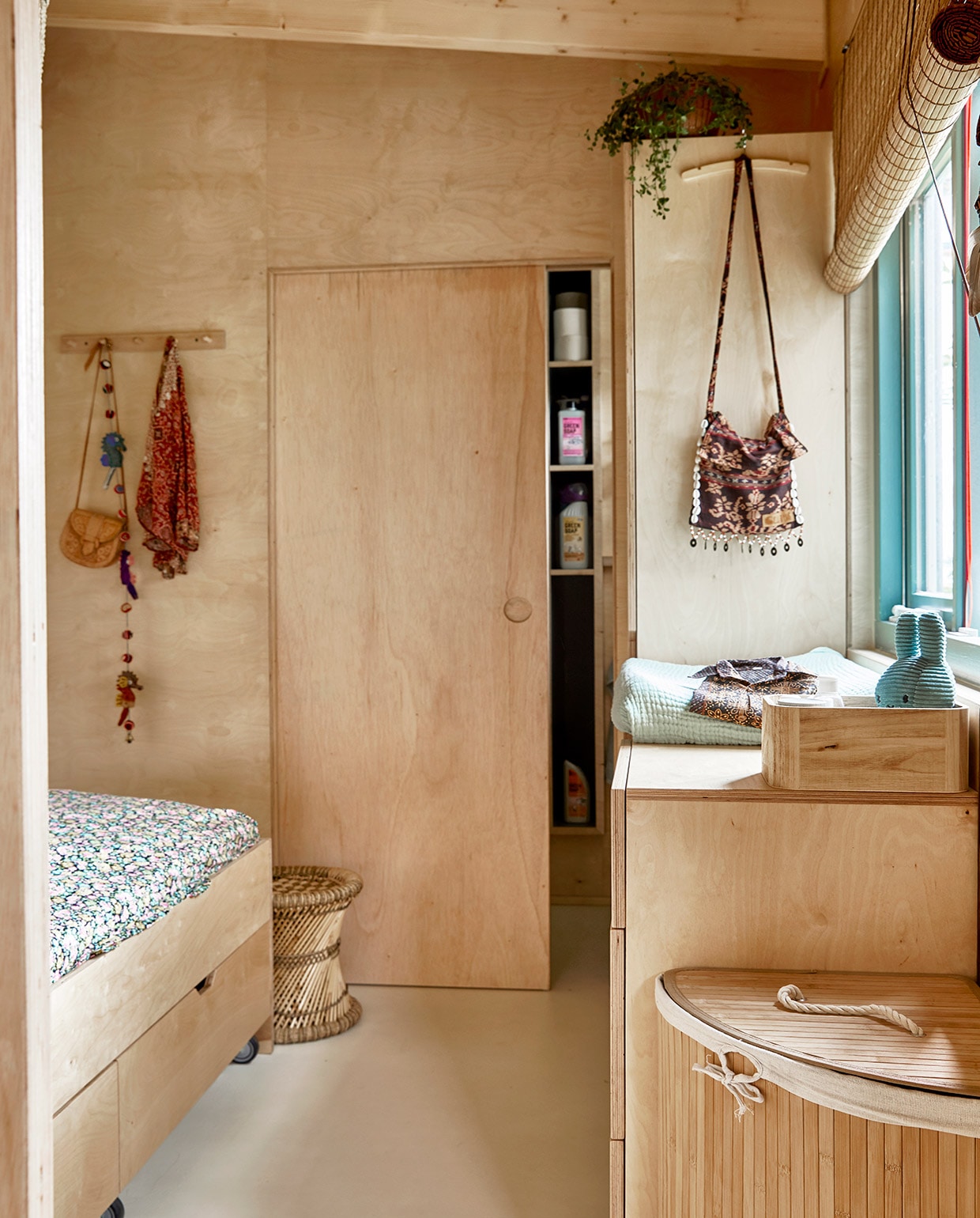 Rieten kruk herkomst onbekend. Beddengoed H&amp;M Home. Leren tasje en kledingstuk souvenir uit Indonesië. Slinger Tastoe. Bruine tas Curms. Aankleedkussen Hema. Houten bakje Kwantum. Nijntje Tastoe. Wasmand Relaxdays. Bamboe rolgordijn Leen Bakker. vtwonen binnenkijken special tiny houses | styling Iris van der Meer | fotografie Peggy Janssen