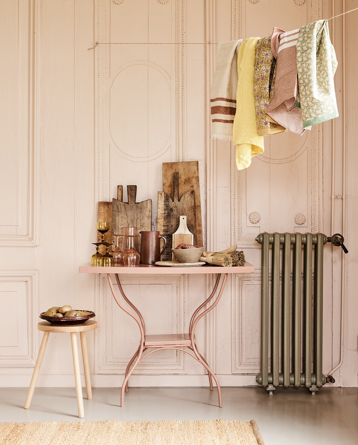 Tafel met ijzeren pootjes, geschilderd in kleur 86DI64 van D’Imago Combitex &amp; Even Anders. Kruk Zara Home. Vloerkleed, theedoek bruin/rood met witte strepen L'etiole Store. Okergele glazen, snijplanken, bruine kan, schaal Jolandelijk. Roze wijnglazen Salon Melrose round, roze glazen kan Salon Melrose S, gele theedoek wafel Lemon, theedoeken met bloemen van Bungalow, geel Lily Masala en groen Nisha Ivy Scandi Living. Beige theedoek met bruine strepen Libeco. vtwonen 05-2021 | styling Marlies Does | fotografie Bart Brussee