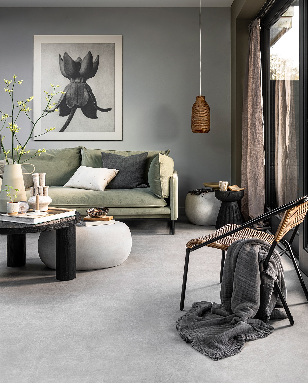 PVC Vloer Basic Light Grey, tegel 91,4×45,7 cm, verkrijgbaar in dryback en click. Ook in de kleur Dark Grey en in XL tegel 91,4×91,4 dryback. M.m.v. , loods5.nl (salontafel Elm), basiclabel.nl (bijzettafels Pebble betonlook van vtwonen, zwarte houten kruk van Woood, fauteuil van BePureHome), sissy-boy.com (vaas met oren, vaas met meerdere halzen, gemarmerde kom, schaal op poot, beker met strepen, kussen met madeliefjes), letoile.store (plantenpot, presse-papier bloem, kandelaar, stoffen etui), paviljoennoord.com (grijs kussen, grijze plaid), hm.com (rotan lamp, gordijn). Overig privébezit. vtwonen 06-2021 | Productie Tanja Saarberg | Styling Danielle Verheul | Fotografie  Sjoerd Eickmans