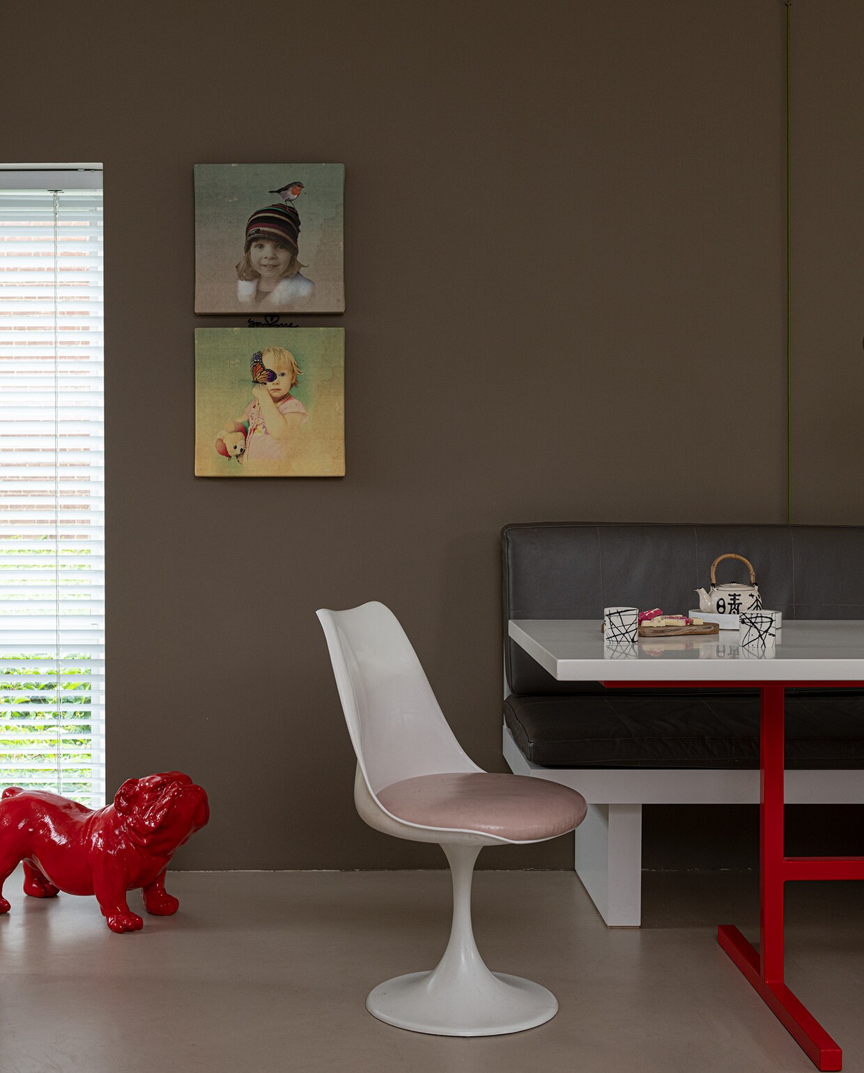 Muurverf Real Grey van Flexa. Schilderijen eigen ontwerp. Bank was een cadeau, de tafel is eigen ontwerp. Stoelen Pastoe. Theepotje kringloopwinkel, marmeren plaatje Sissy-Boy, porseleinen kopjes Henk Wolvers. Rood kunstwerk van hond is een Engelse Bulldog Ceasor. vtwonen 04-2021 | Styling Sharon Roest | Fotografie Caroline Martinot
