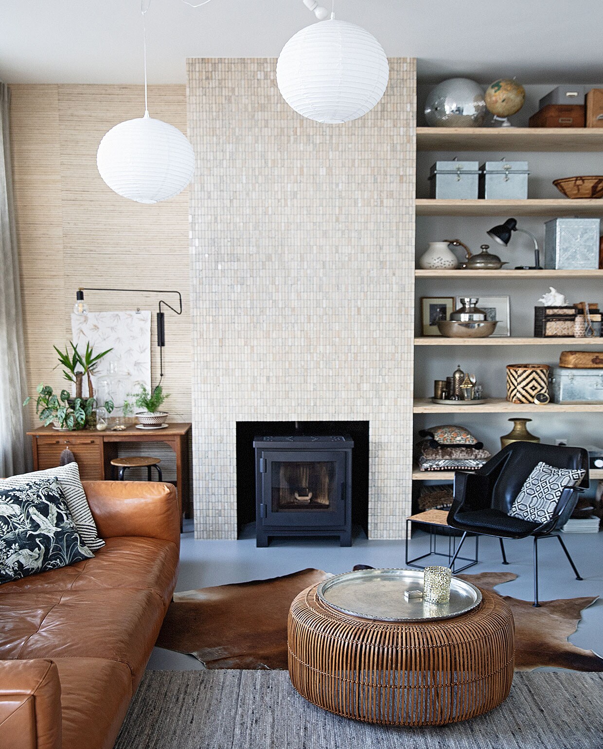 Behang Natural Wall Coverings Eijffinger, tegels natuursteen Praxis, muurverf Papyruswit Ral 8018 Flexa, plafondverf Powerdek Ral 9010 Flexa, planken underlayment. Kachel Arya van Nordic Fire, bureau kringloop Het Goed, zwarte wandlamp House Doctor, zandloper Laif &amp; Nuver, schelp Bij Risje Ameland. Witte lampen Praxis, snoer Snoerboer, bank Het Anker, dierenvel Ikea, vloerkleed Woontheater de Eclips, fauteuil Gispen 416 van Dutch Originals, bijzettafel en kussen vogel zelfgemaakt, kussen strepen Home Delight. Salontafel en waxinelichthouder HKliving, dienblad Ottomania.In kast: vaas met kraanvogels Piet Hein Eek, rotan mand Laif &amp; Nuver, bovenste kussen zelfgemaakt, middelste kussen Kleur op Kleur Interieur, onderste kussen Imbarro, platenspeler Crosley, grote schelp en Matroesjka Bij Lokaal, klok Karwei. Overig vintage of souvenir. vtwonen 04-2021 | productie en styling Ilona Jongepier | fotografie Dana van Leeuwen | tekst Anna van der Heijden