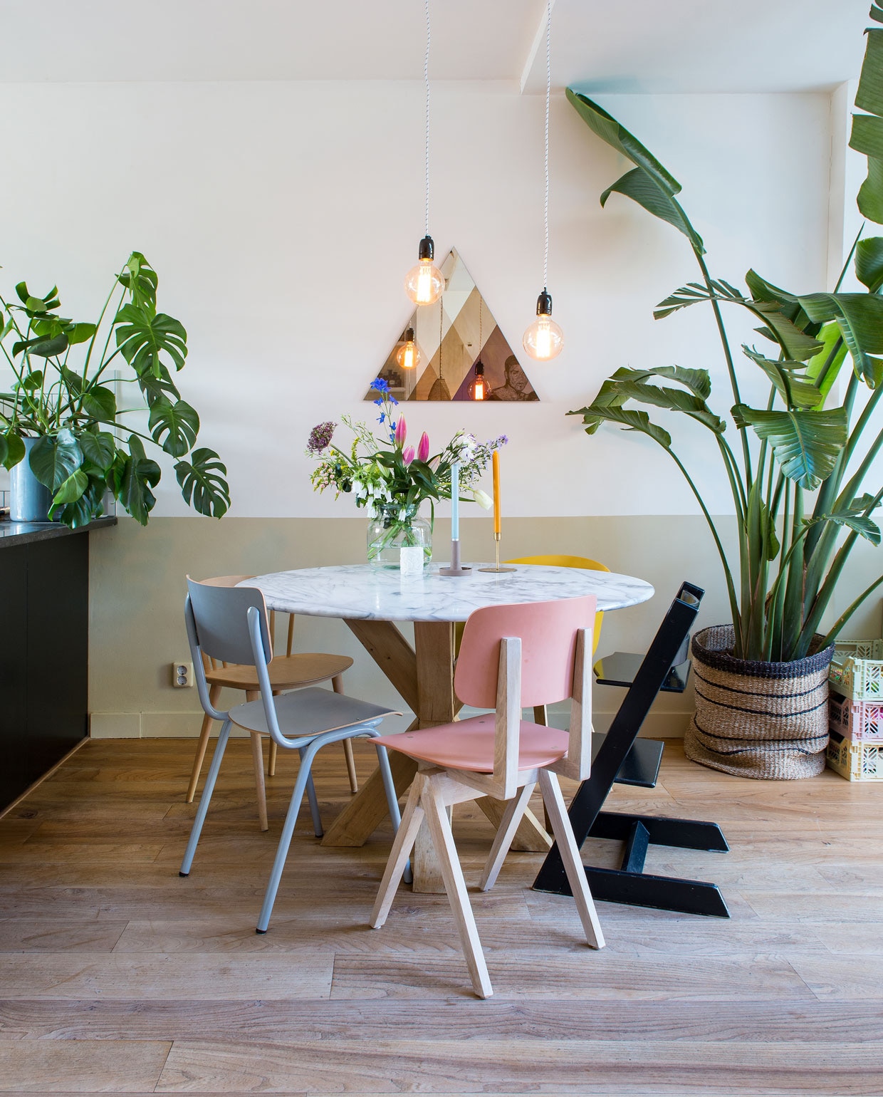 Eettafel met marmeren blad van Marktplaats, eikenhouten kruispoot gemaakt door een timmerman. Roze stoel Galvanitas en grijze stoel Back to School van Zuiver via Loods 5, houten stoel J104 en gele stoel AAC22 van Hay, zwarte Tripp Trapp stoel Stokke. Transcience spiegel Lex Pot, lampen Bailey, mand Sissy-Boy, planten Strelizia Nicolai Primavera en Monstera, kratten Aykasa. De vloer is van lokaal iepenhout. vtwonen 03-2020