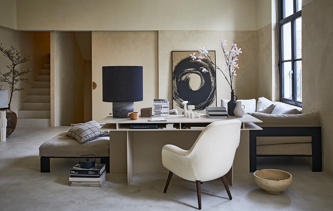 Bureau op maat gemaakt (com-anders.nl). Fauteuil Swoon van Fredericia (designtales.nl). Linnen bank met stalen frame, prijs op aanvraag, lamp met grote kap, papier-maché schaal, muur- en vloer, prijs op aanvraag (anoukb.com). Schilderij, prijs op aanvraag (tessaderijk.com), geruite kussens 50×50 cm (fermliving.com). Grijze organizer Muuto (nordicnew.nl). Witte hoge vaas, zwarte vaas, witte kleine vaas, suède dozenset van 3 (nordal.eu). Zwarte theepot Serax Collage 1,2 l (vtwonen.nl). Overig privébezit. vtwonen 04-2021 | Styling Cleo Scheulderman | Fotografie Jeroen van der Spek