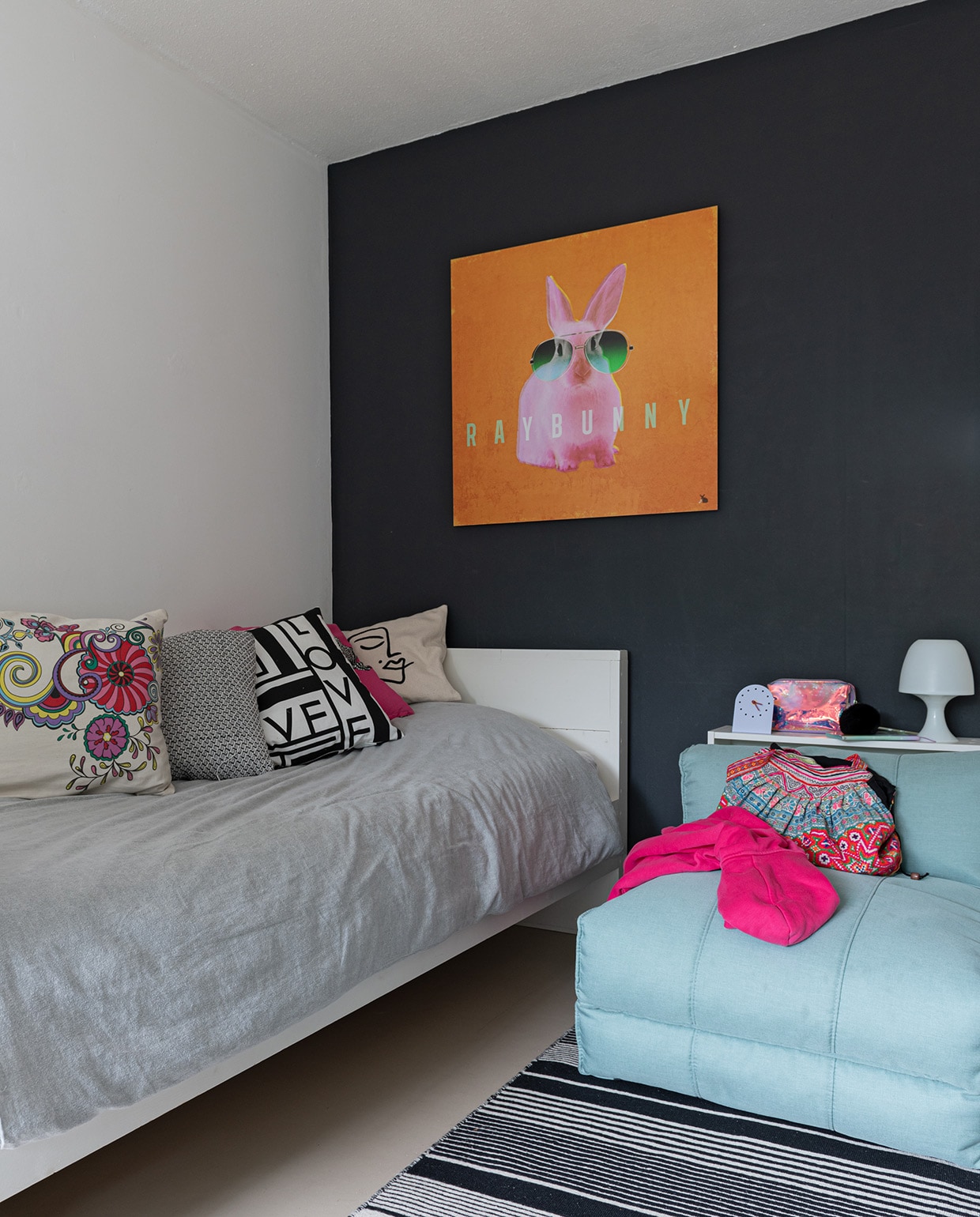 Muurkleur Zwart Flexa. Bedbank van Marktplaats, kussens Ikea, blauwe fauteuil Home 24. Kleed en klok Ikea. Lampje Hema. Muurversiering eigen ontwerp. vtwonen 04-2021 | styling Sharon Roest | fotografie Caroline Martinot