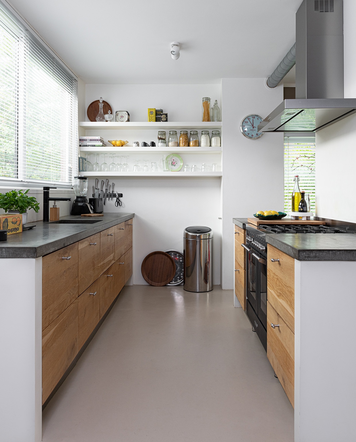 Keuken Ikea, fronten door Koak design, fornuis Fratelli Onofri, afzuigkap Falmec. Marmoleumvloer Walton van Forbo vloeren. Prullenbak Brabantia. Bruin dienblad H&amp;M Home, zilveren dienblad Turkse winkel. Op het aanrecht: snijplank Ikea, fruitschaal vintage. Klok Cabanaz. Op de planken: glaswerk voornamelijk Ikea, dienblad H&amp;M Home. Aan de muur: messenset Berlinger Haus. Blender Bosch. Bakje souvenir uit Mexico. vtwonen 04-2021 | styling Sharon Roest | fotografie Caroline Martinot