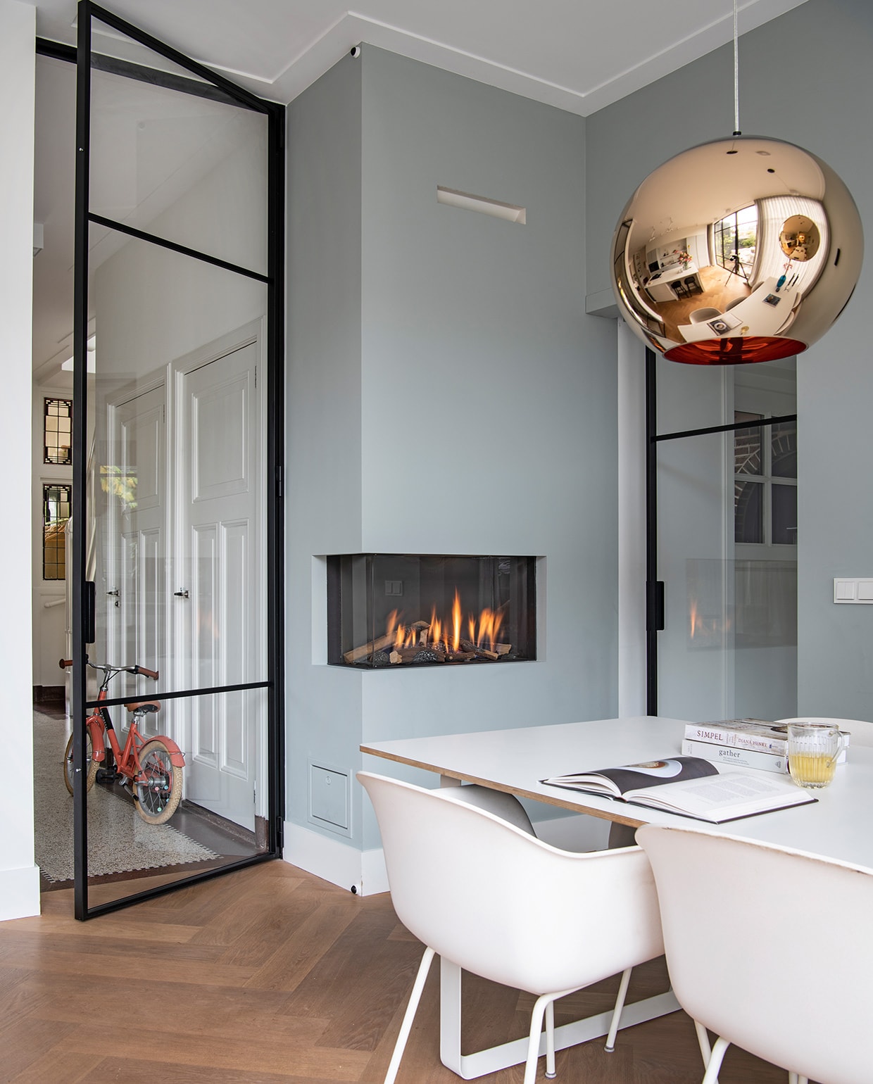 Muurverf Light Blue 22 van Farrow &amp; Ball. Vloer eiken. Tafel en stoelen Muuto. Hanglamp Tom Dixon. Glas HKliving. Elektrische open haard Element4. Fiets Veloretti. Glazen deuren gemaakt in Polen. vtwonen 04-2021 | Styling Inge van Lieshout | Productie Insidehomepage | Fotografie Louis Lemaire | Tekst Inge van Lieshout | Tekstbewerking Anna van der Heijden