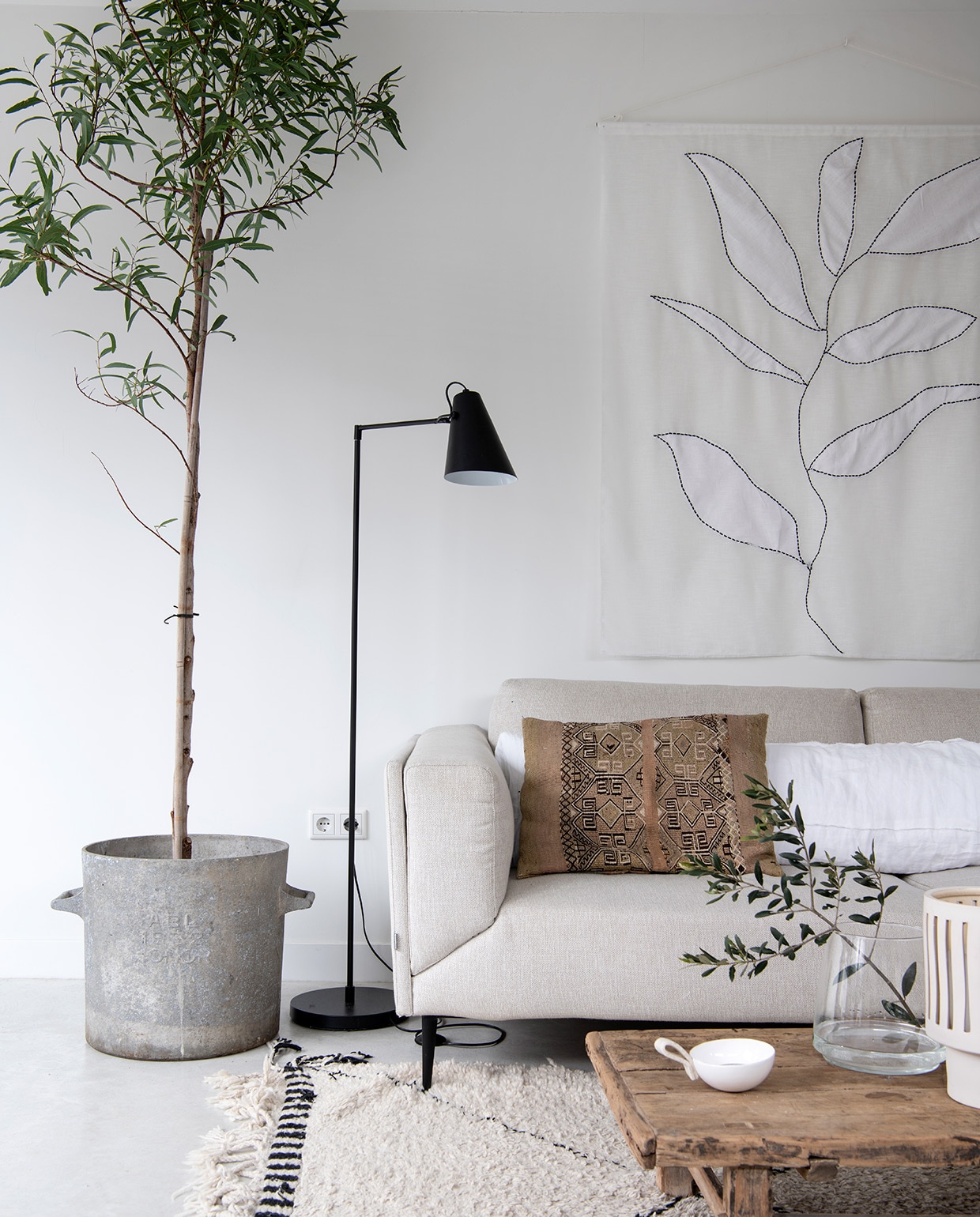 Bank Feelings Wonen, bruine kussens uit Marrakech, overige kussens en kunstwerk Huize Jolie. Plant Budgetplant. Vloerlamp vtwonen. Kleed Marktplaats, koffietafel Cooperz Wonen, vaas Hoy Concept Shop. Bloempot Bloomingville. Pluimen uit de tuin van Jolies moeder, XL-vaas Van Hees Design. Overig herkomst onbekend. vtwonen 04-2021 | styling Marit Saladini | fotografie Louies Lemaire | tekst Christien Jansen
