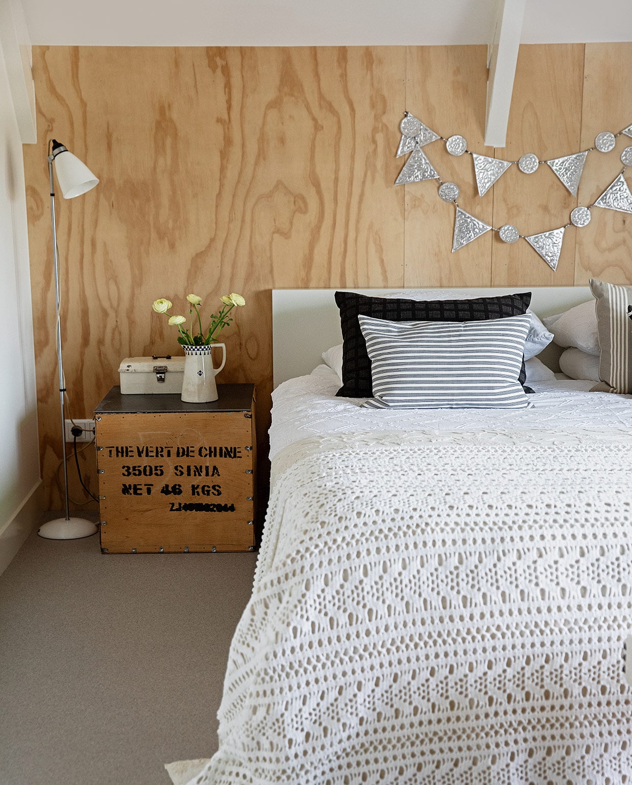 Vloer Briljant Project van Interfloor, bed Ikea, lamp Pols Potten, theekist gevonden op straat in Groningen met ijzeren blad gemaakt door vriend van Rudie, broodtrommel en slinger Bij Lokaal, kan Carlotte Antiek en Brocante, gestreepte kussens zelf gemaakt van vintage katoenen stoffen van grootouders, zwart kussen Kleur op Kleur Interieur, wit beddengoed Livello, sprei Crewel, gehaakte sprei gemaakt door Rudies moeder. vtwonen 04-2021 | productie en styling Ilona Jongepier | fotografie Dana van Leeuwen