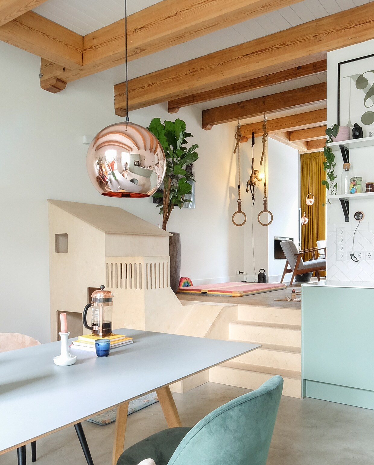 Tafel Hay. Hanglamp Tom Dixon. Herkomst stoelen onbekend. Kandelaar Hay. Cafetière Bodum. Speelhuis gemaakt door Plantvierkant. Speelmat ByAlex Playmats. Mand Ikea. Houten speelgoedvrachtwagen Fagus. Wandlamp Lucide. Gymnastiekringen uit een oude gymzaal. Turnmat Neef Louis. Aaplamp Seletti. Pot met ficus lyrata Intratuin vtwonen 03-2021 | productie Coco features | styling Gerlise van Putten | fotografie Sabine Burkunk