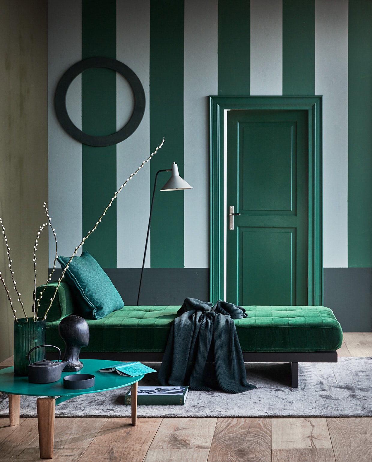 Muurverf wand links Camouflage, gestreepte wand Moss en Soap, lambrisering Bottle, op deur lakverf Moss. M.m.v. covanderhorst.nl (daybed van de Sede, salontafel van Arflex), design020.nl (plaid van Muuto), goeds.nl (vloerlamp), nordal.eu (object hoofd, theepot, vloerkleed), festamsterdam.com (schaal), hm.com (vaas), vtwonen.nl (kussen van Hay). vtwonen 04-2021 | Styling Cleo Scheulderman | Fotografie Jeroen van der Spek