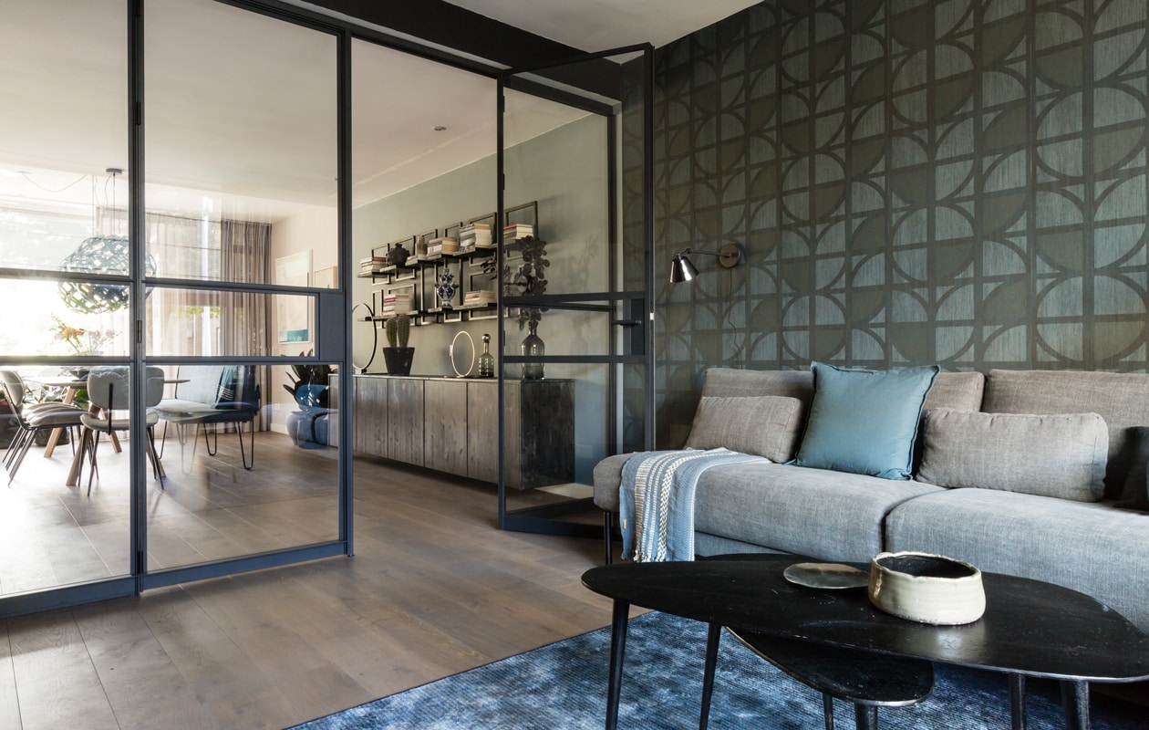 Kleur op de muur ‘Royal Blue’ Flexa. Behang uit de collectie Bold 395813 Eijffinger. Gordijnen uit de collectie Naomi 7975-7 Eijffinger via Woninginrichting-Aanhuis.nl. Glazen pui GewoonGers. Kunstwerken Werk aan de Muur. Bank en fauteuil Eijerkamp. Bijzettafelset Basiclabel.nl. Vloerkleed Eijerkamp. Salontafel tussen de banken BoxWorx. Wandlamp Tonone. Vloerlamp Eijerkamp. Kandelaar 12-armig, plaid en kussens vtwonen. Hoge vaas House Doctor. Bordje zilverkleurig &amp;Klevering. Overig privébezit. vtwonen Weer verliefd op je huis seizoen 11, aflevering 12 | styling Fietje Bruijn