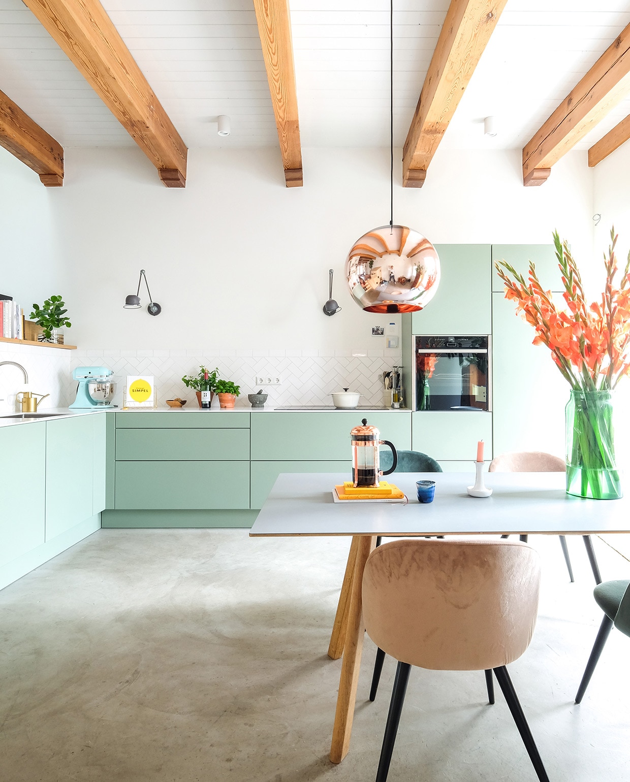 Keuken Next125, kleur Sage. Tafel Hay. Hanglamp Tom Dixon. Herkomst stoelen onbekend. Vaas Bloemetje Op Tafel. Kandelaar Hay. Cafetière Bodum. Pan Ikea. Wandlampen Lucide. Keukenmachine KitchenAid. Kraan Quooker. Schappen Ikea. vtwonen 03-2021 | productie Coco features | styling Gerlise van putten | fotografie Sabine Burkunk