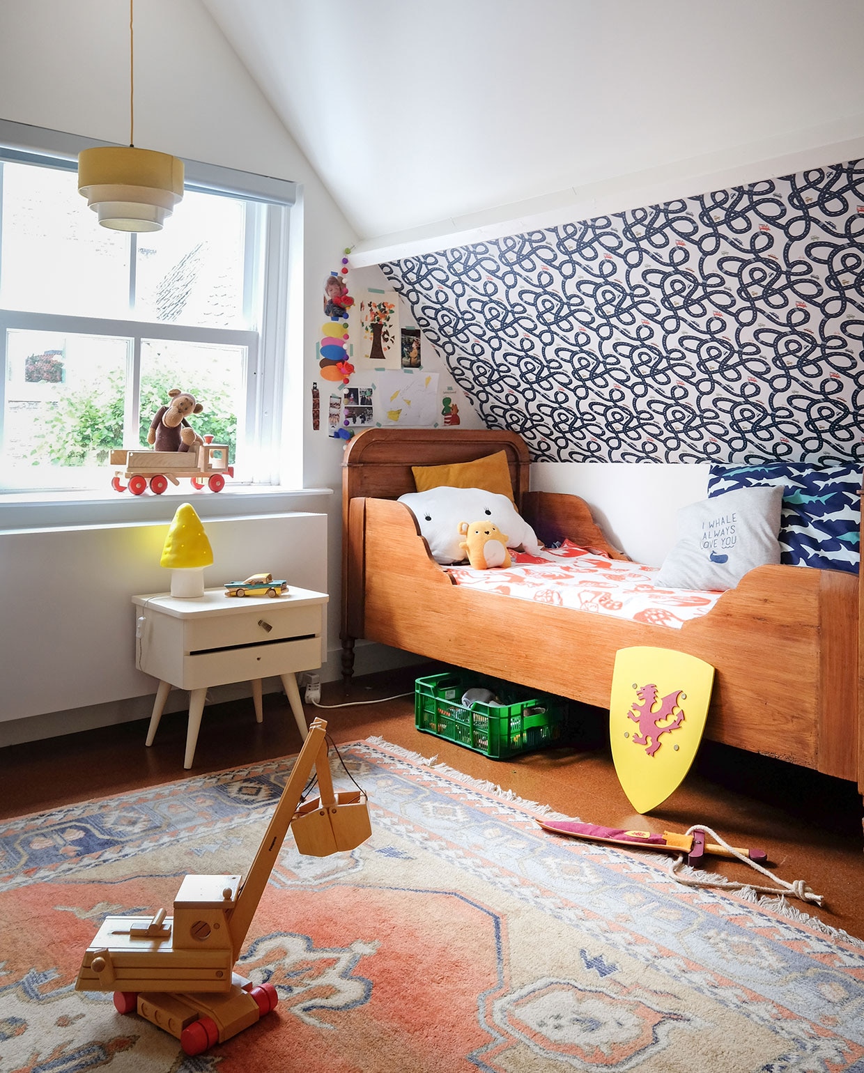 Houten bed en kleed Marktplaats. Houten speelgoed Marktplaats en souvenirs van reizen. Speelgoedkraan Fagus. Behang ByAlex. Kastje vintage. Lamp Heico. Beddengoed Hema. Gele knuffel en kussenknuffel Noofoll, aapje zelfgemaakt. Wapenschild souvenir uit Frankrijk. vtwonen 03-2021 | productie Coco features | styling Gerlise van putten | fotografie Sabine Burkunk