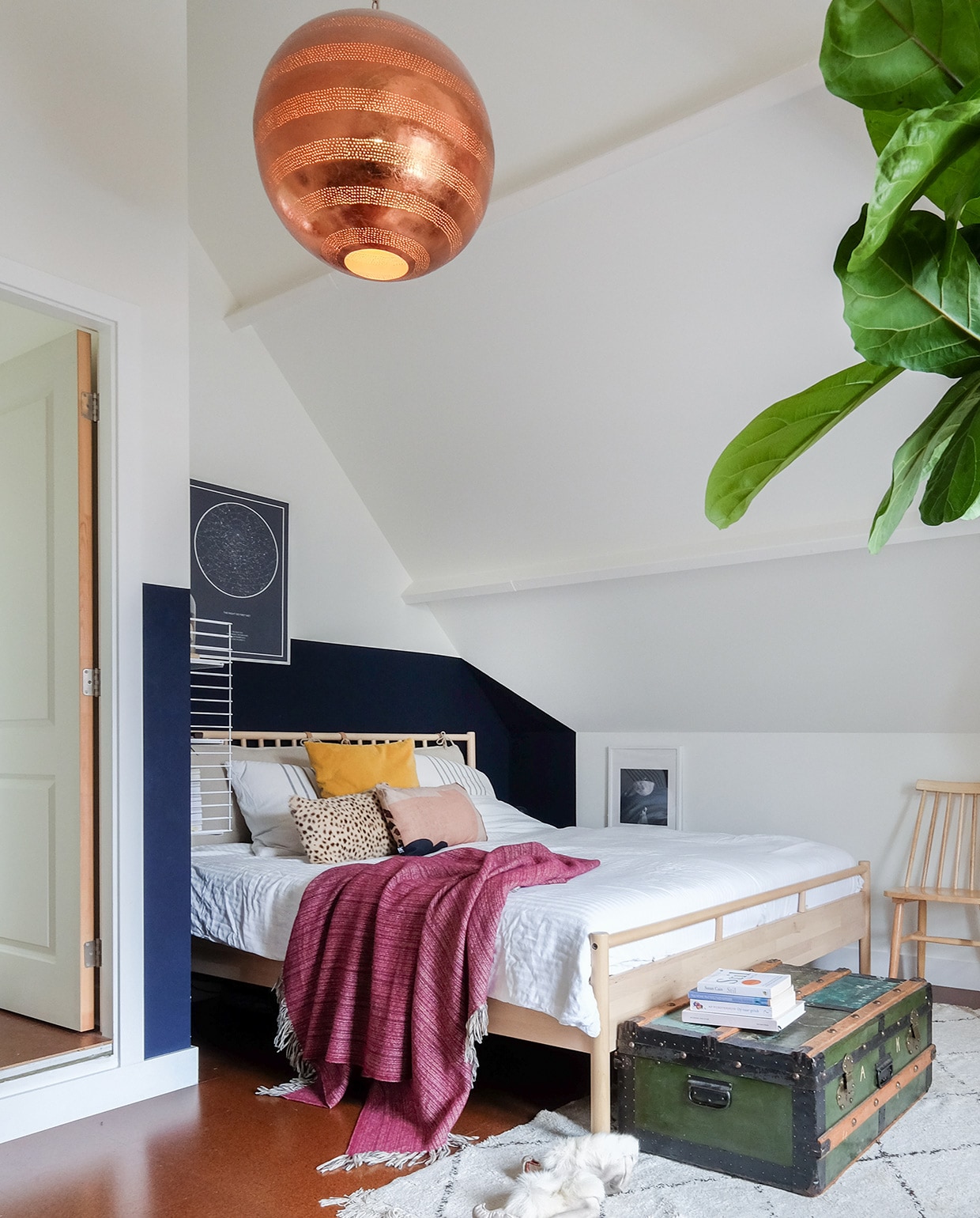 Bed met hoofdbord en vloerkleed Ikea. Kist van Oscars opa. Rendiersloffenuit Lapland. Poster The Night Sky. Beddengoed H&amp;M Home. Hanglamp uit India. Houten stoel Tressia van Kave Home. vtwonen 03-2021 | productie Coco features | styling Gerlise van putten | fotografie Sabine Burkunk