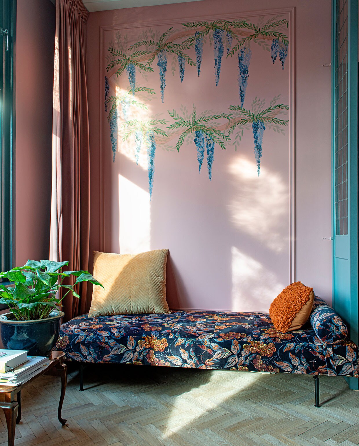Visgraatvloer Loven Dageraad Vloeren. Muurverf Hellebore 275 van Little Greene. Verf paneel De Nimes van Farrow &amp; Ball. Muurschilderingen zelfgemaakt. Daybed Karwei, geel kussen H&amp;M Home, oranje kussen Jysk. Bijzettafel kringloopwinkel, plantenpot gekregen. Gordijnen Leen Bakker. vtwonen 03-2021 | Fotografie Caroline Coehorst | Tekst Adeline Mans
