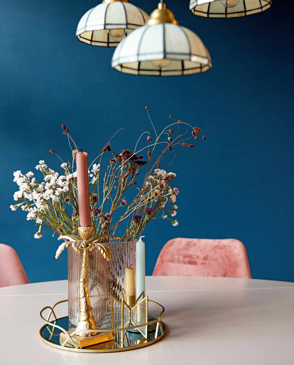 Eettafel kringloopwinkel, eetkamerstoelen Kick Collection. Kleine vaas Jysk, bloemen zelf gedroogd. Kandelaar palmboom gekregen, gouden kandelaars en spiegelplateau Sissy-Boy. vtwonen 03-2021 | Fotografie Caroline Coehorst | Tekst Adeline Mans