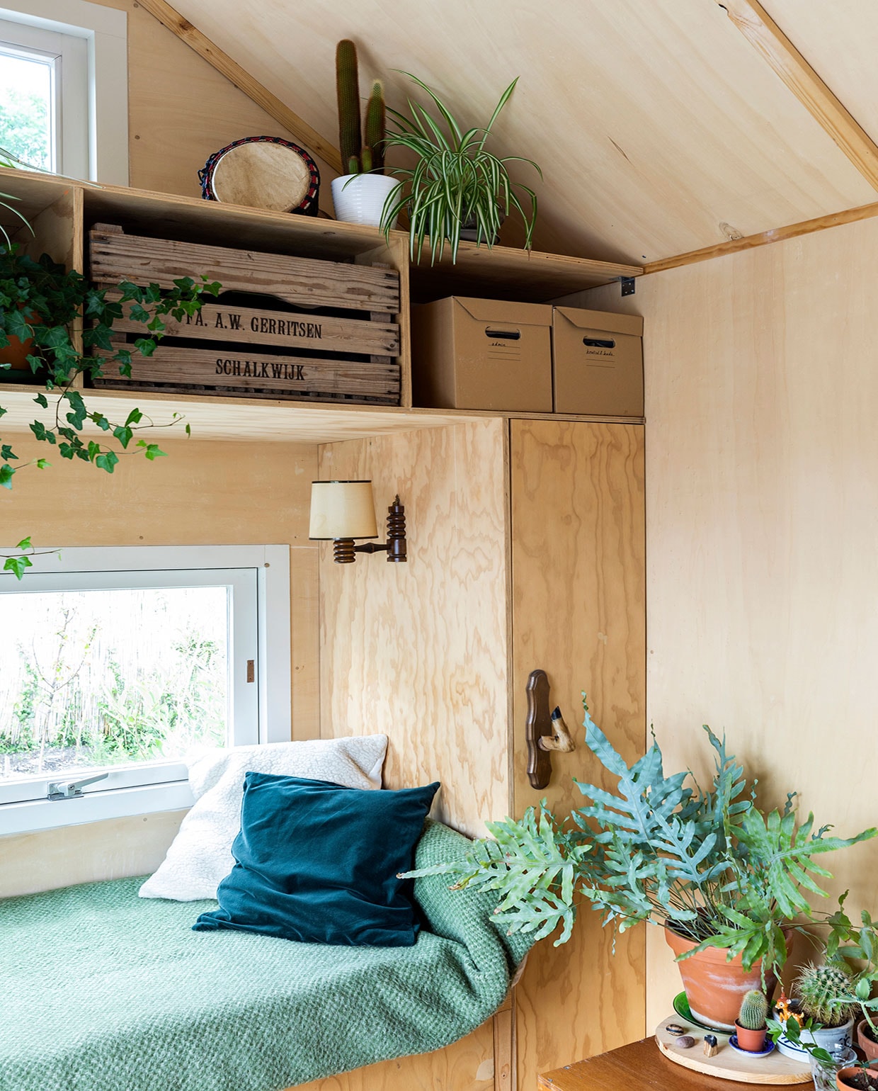 Lampje en deken van de kringloop. Kussens zelfgemaakt, onder andere van oude, wollen onderdekens. De administratie is opgeborgen in een houten groentekrat. vtwonen special tiny houses 2021 | Fotografie Margriet Hoekstra